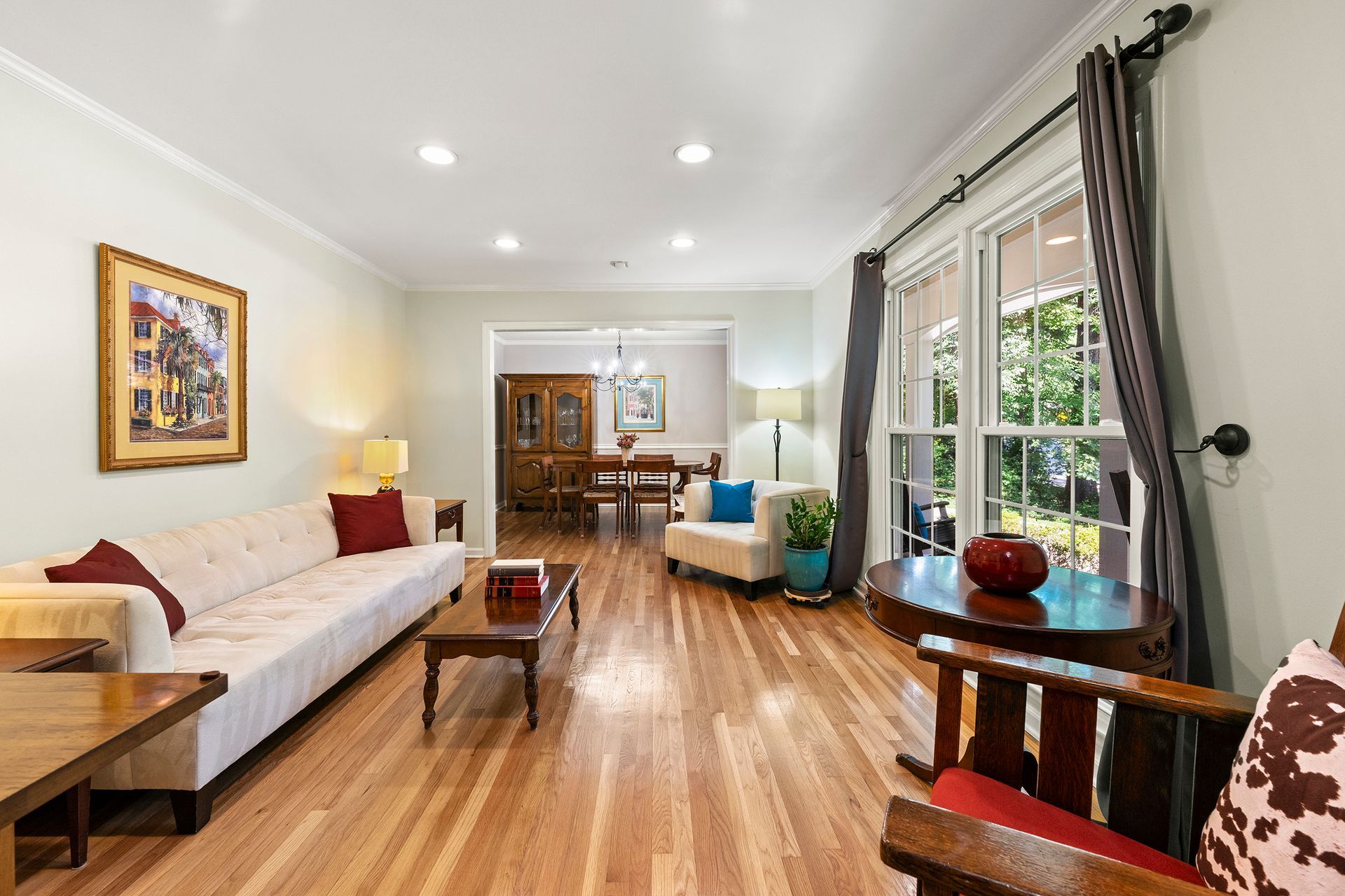 A living room with hardwood floors , a couch , chairs , and a table.