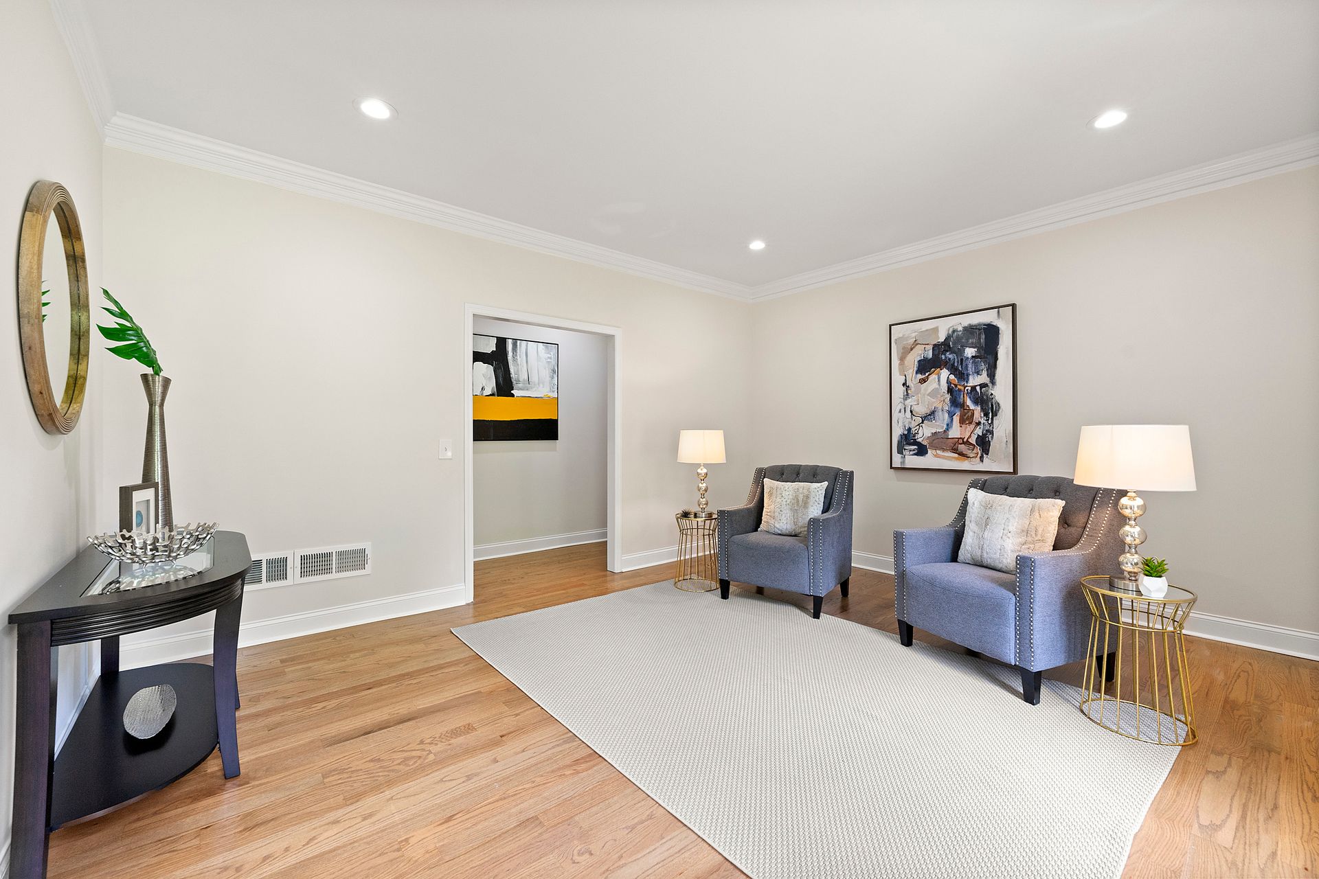 A living room with two chairs , a table and a rug.