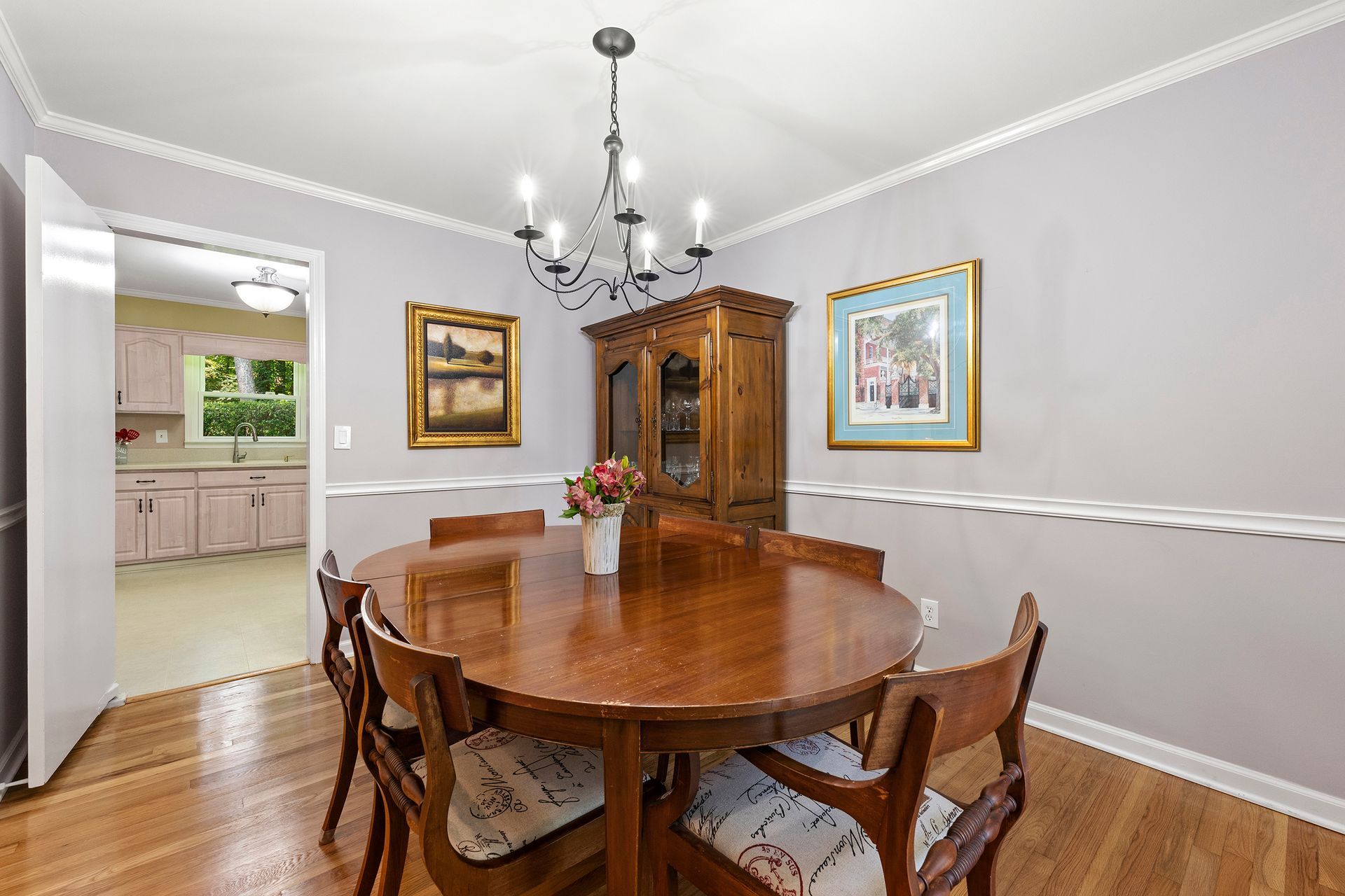 A dining room with a round table and chairs and a chandelier.