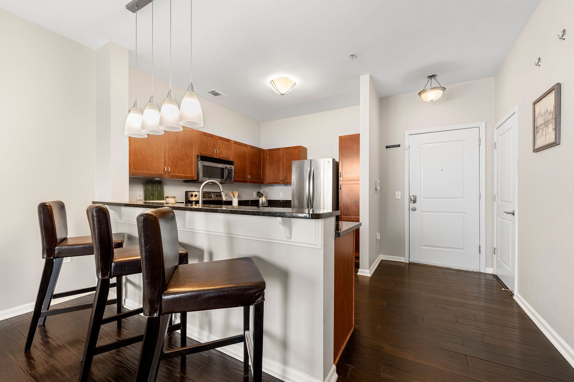 A kitchen with a bar , stools and a refrigerator.