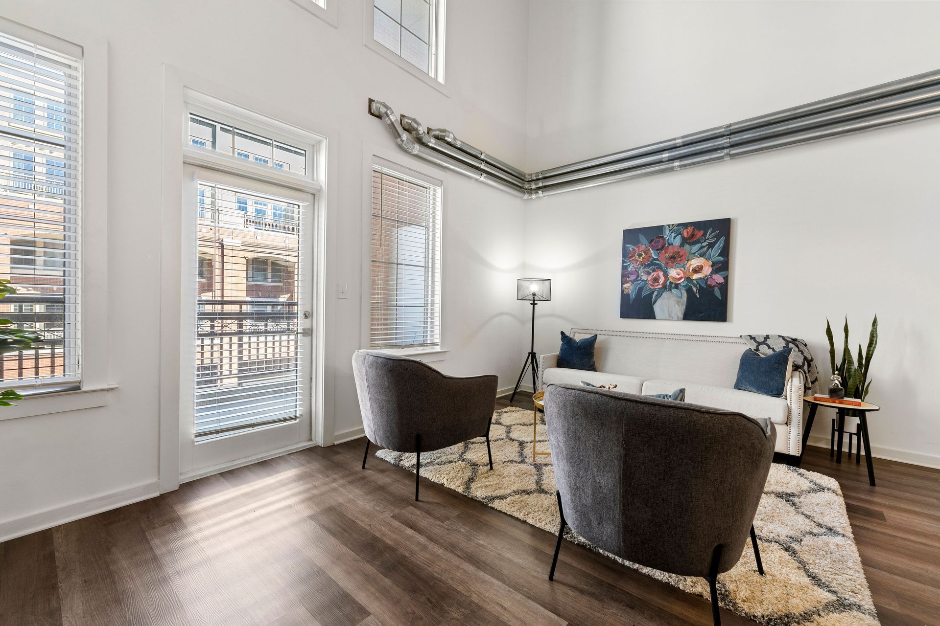 A living room with a couch , two chairs , a rug and a balcony.