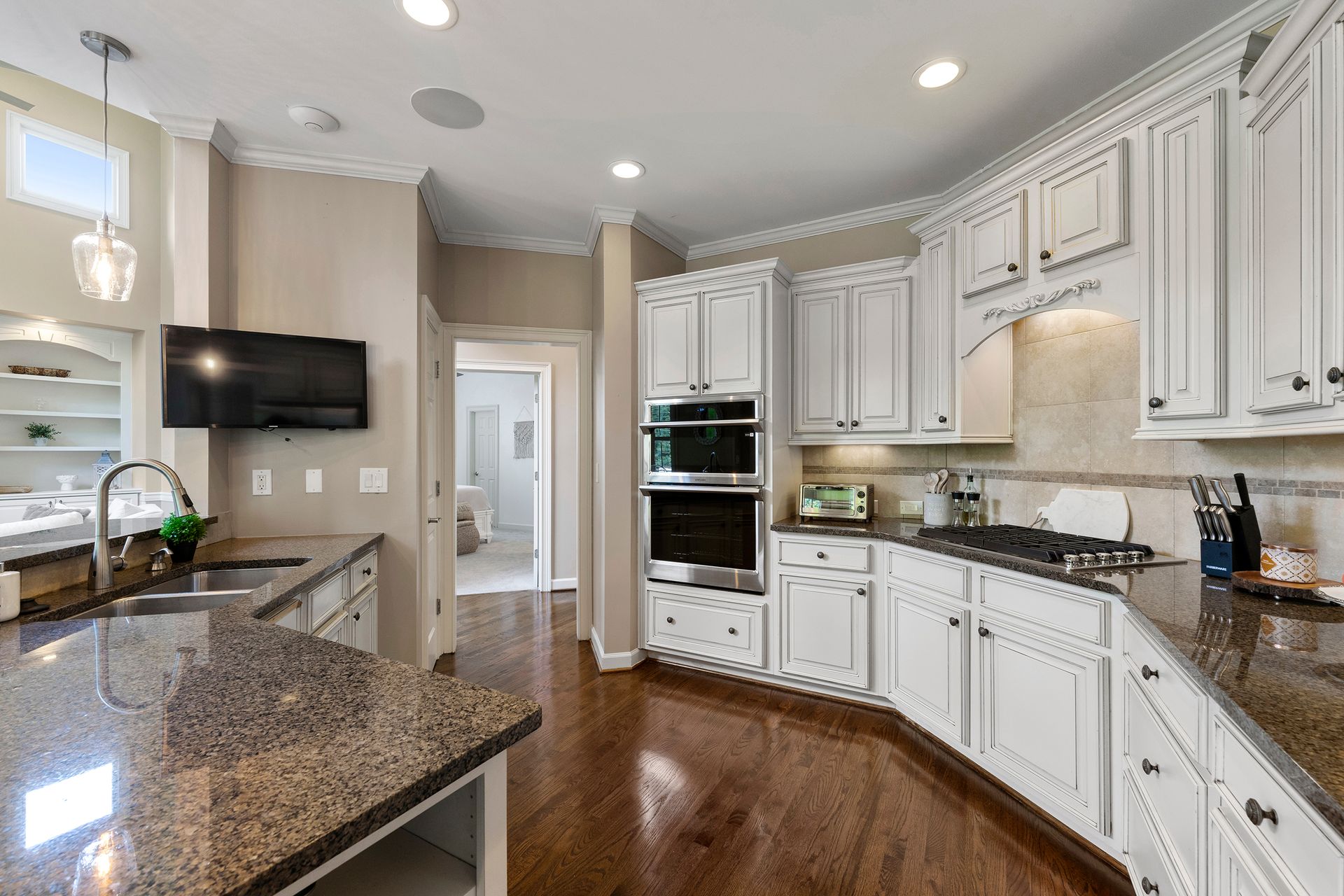 A kitchen with white cabinets , granite counter tops , and stainless steel appliances.