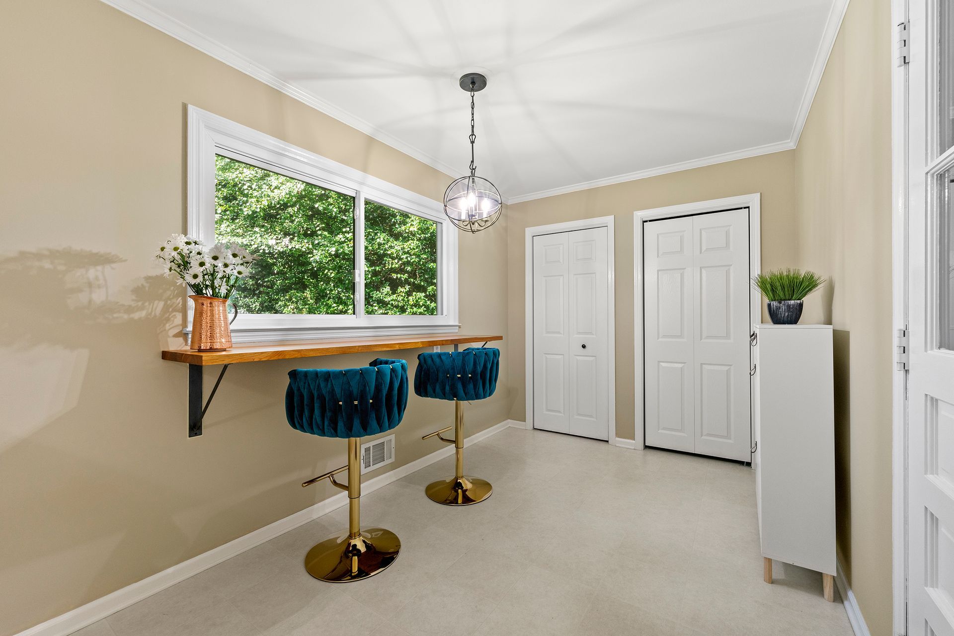 A room with two bar stools , a desk and a window.