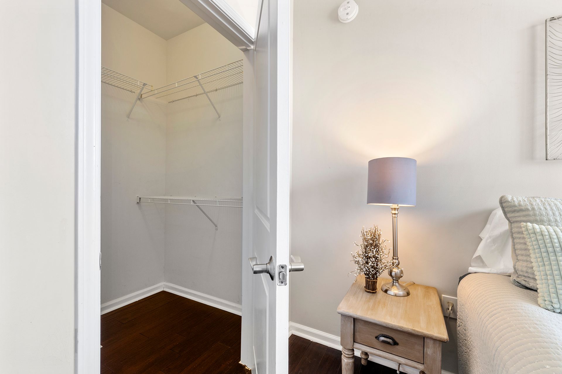 A bedroom with a walk in closet and a nightstand.