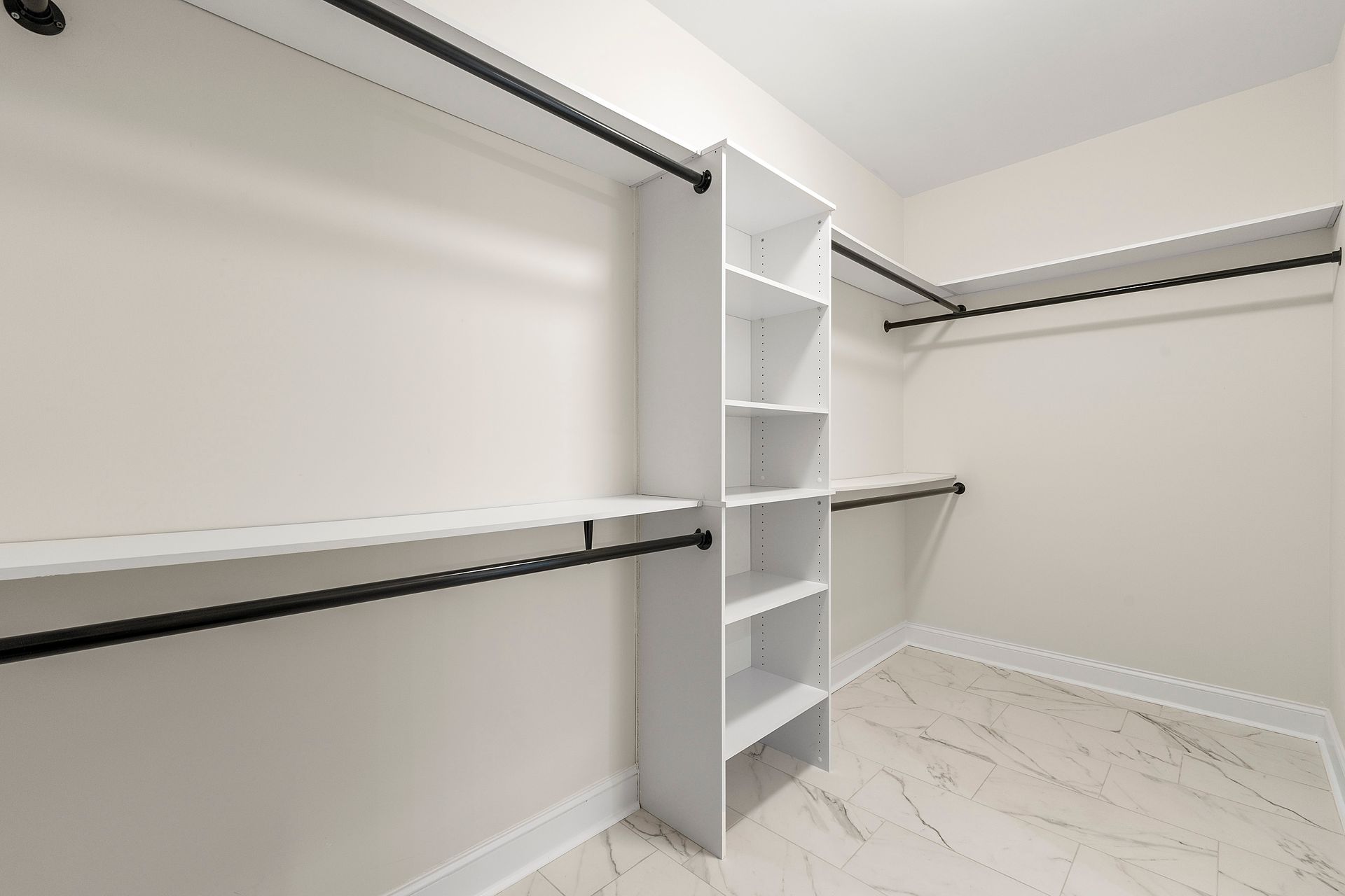 An empty walk in closet with shelves and clothes racks.