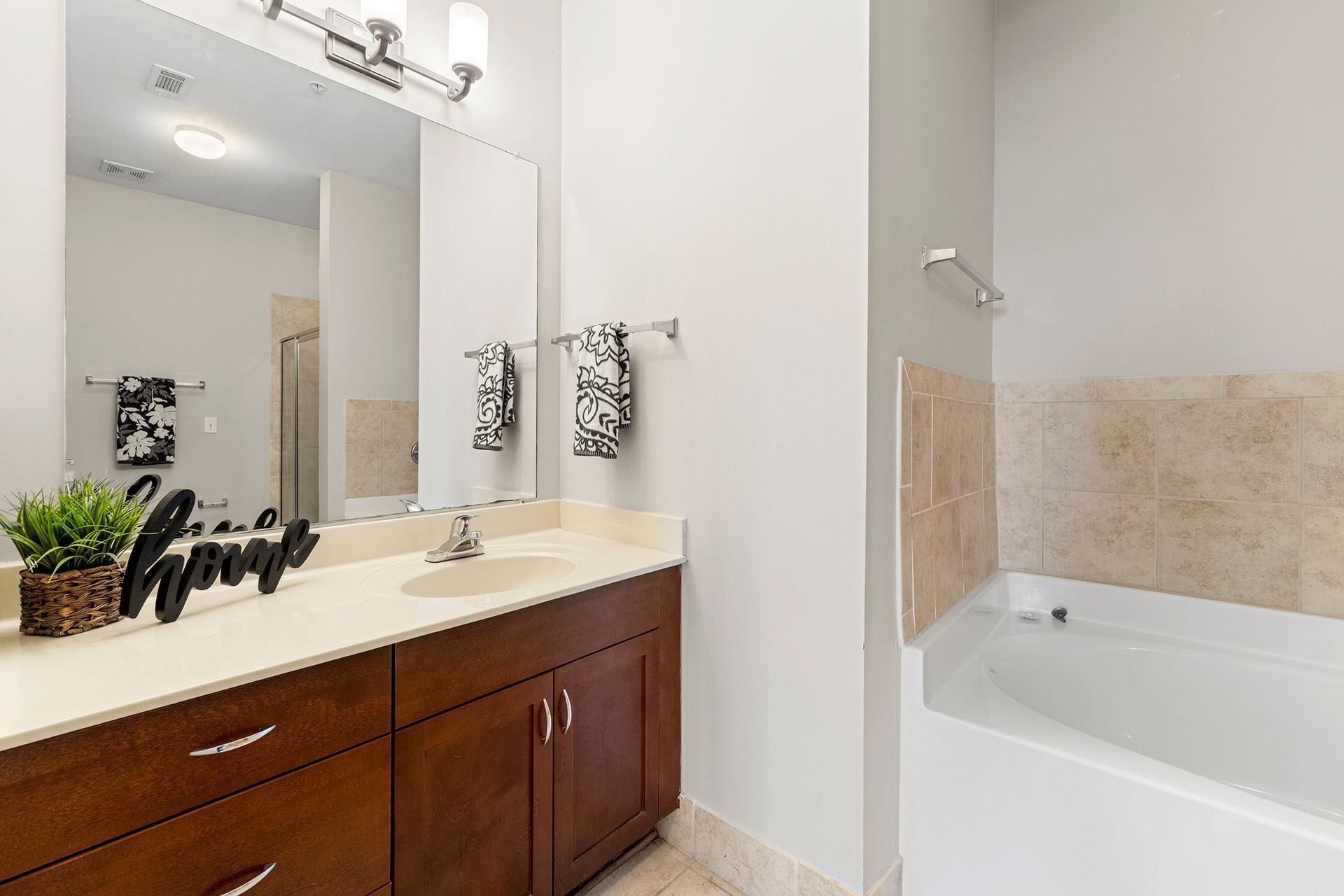 A bathroom with a sink , mirror and bathtub.