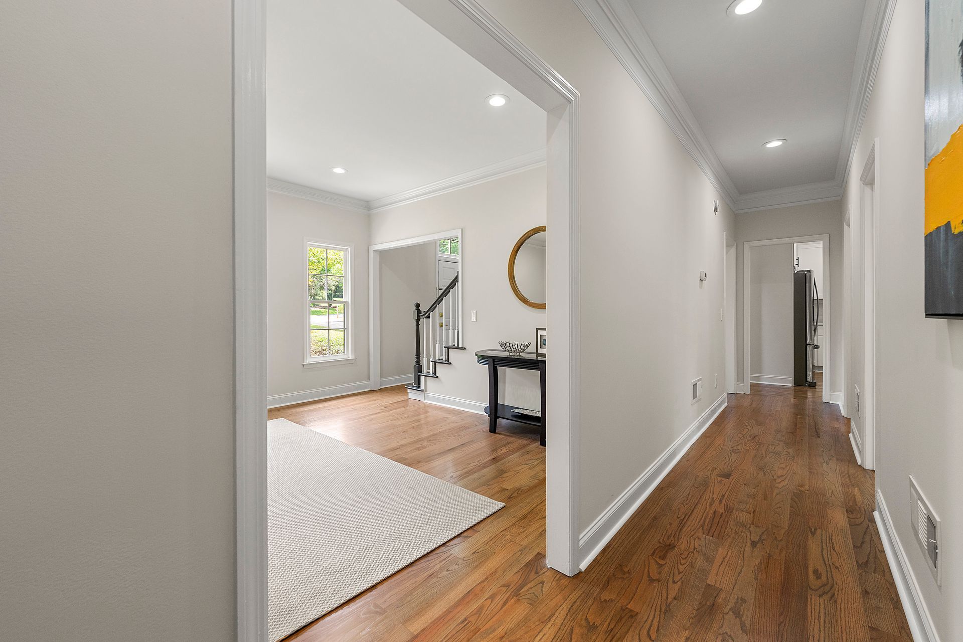 A long hallway in a house with hardwood floors and white walls.