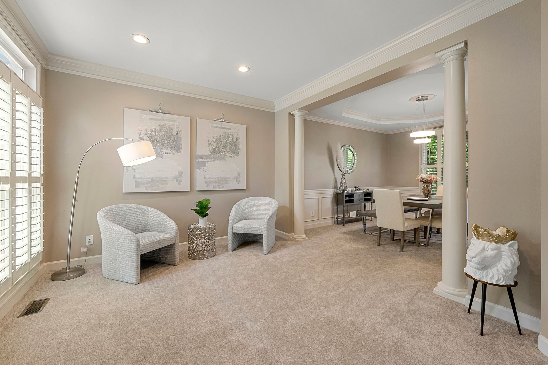 A living room with two chairs and a lamp and a dining room in the background.
