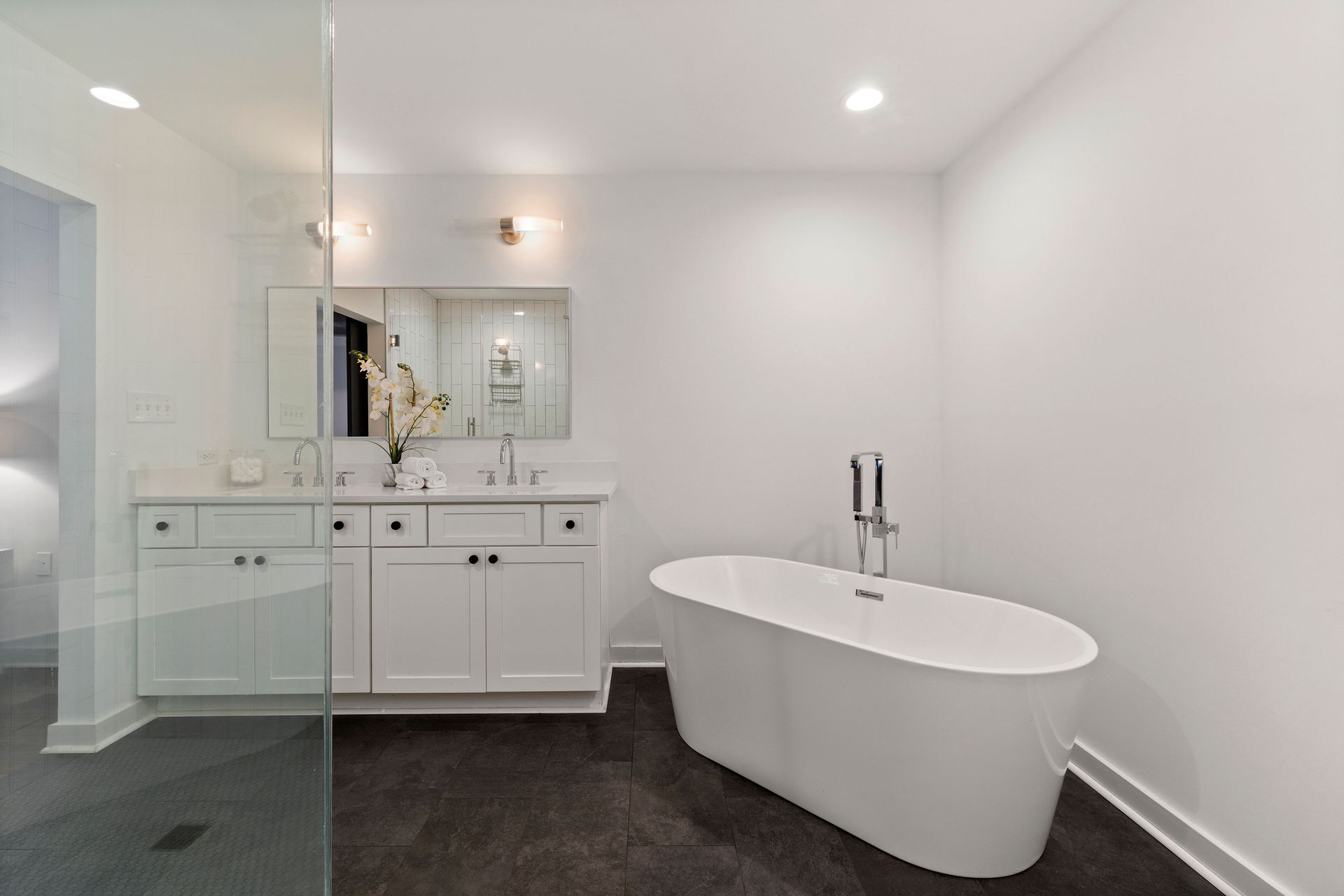 A bathroom with a tub , sink , mirror and walk in shower.