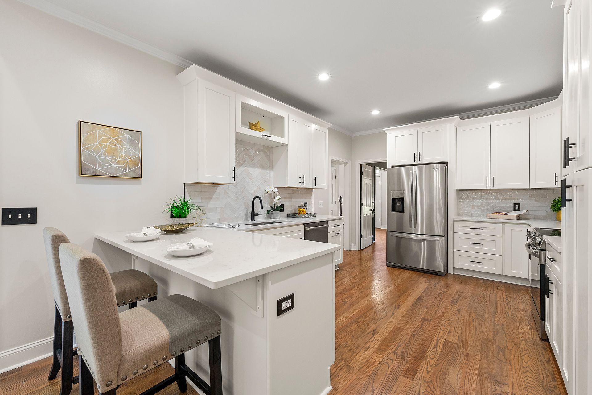 A kitchen with white cabinets , stainless steel appliances and hardwood floors.