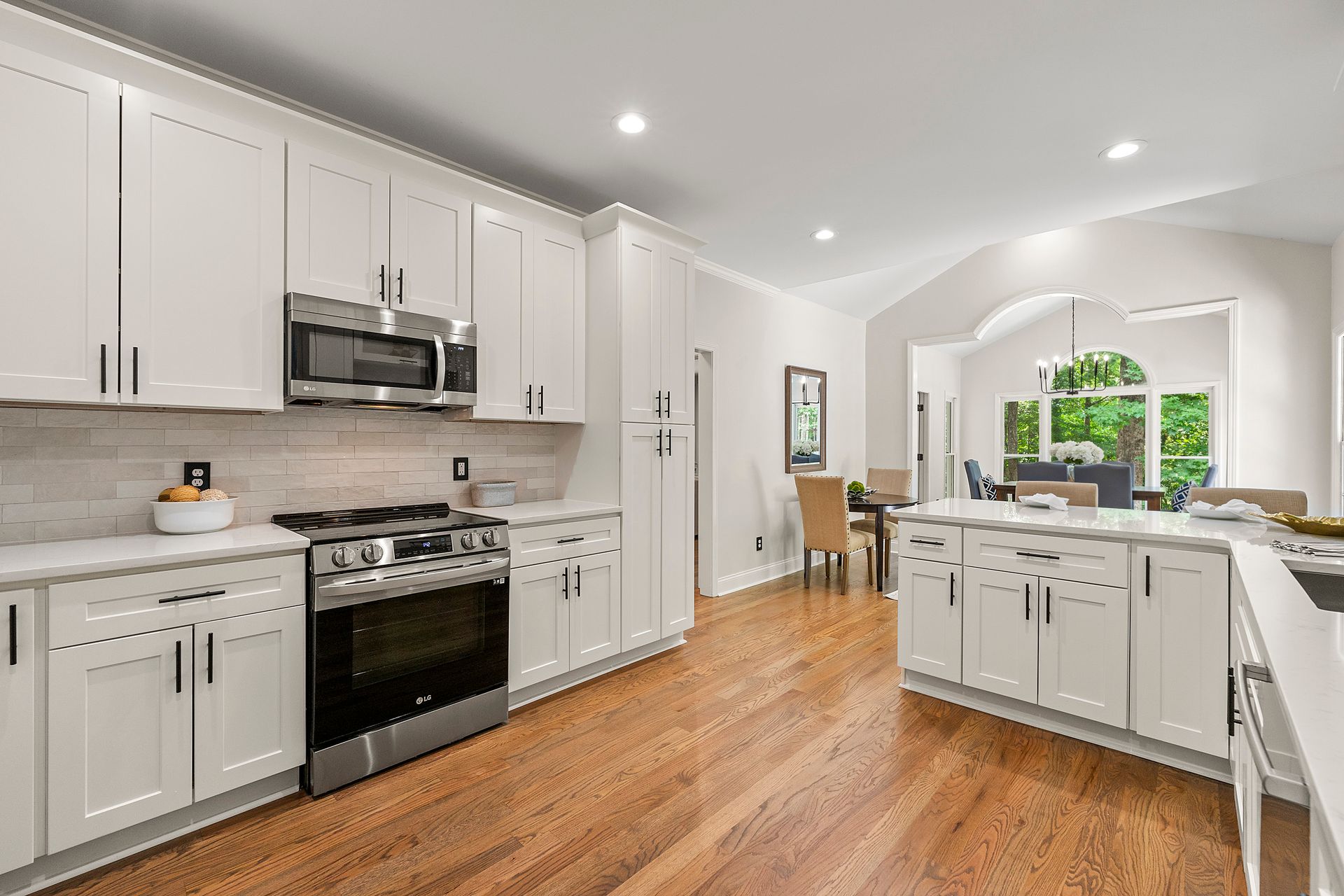 A kitchen with white cabinets , stainless steel appliances , and hardwood floors.