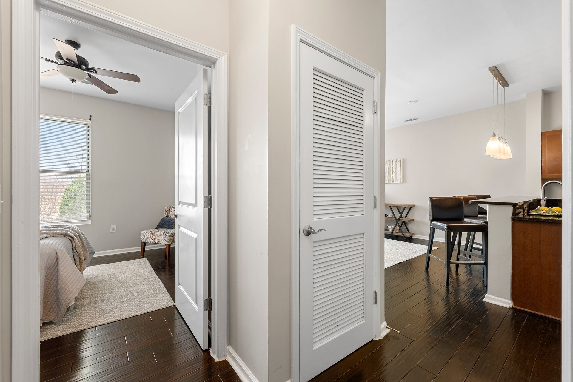 A hallway in a house with hardwood floors and a ceiling fan.