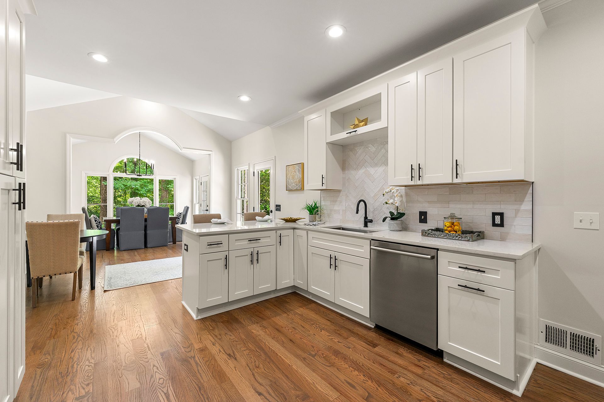A kitchen with white cabinets and stainless steel appliances and hardwood floors.
