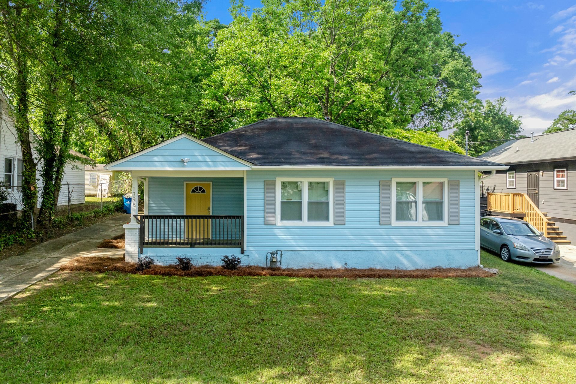 A small blue house with a yellow door and a car parked in front of it.