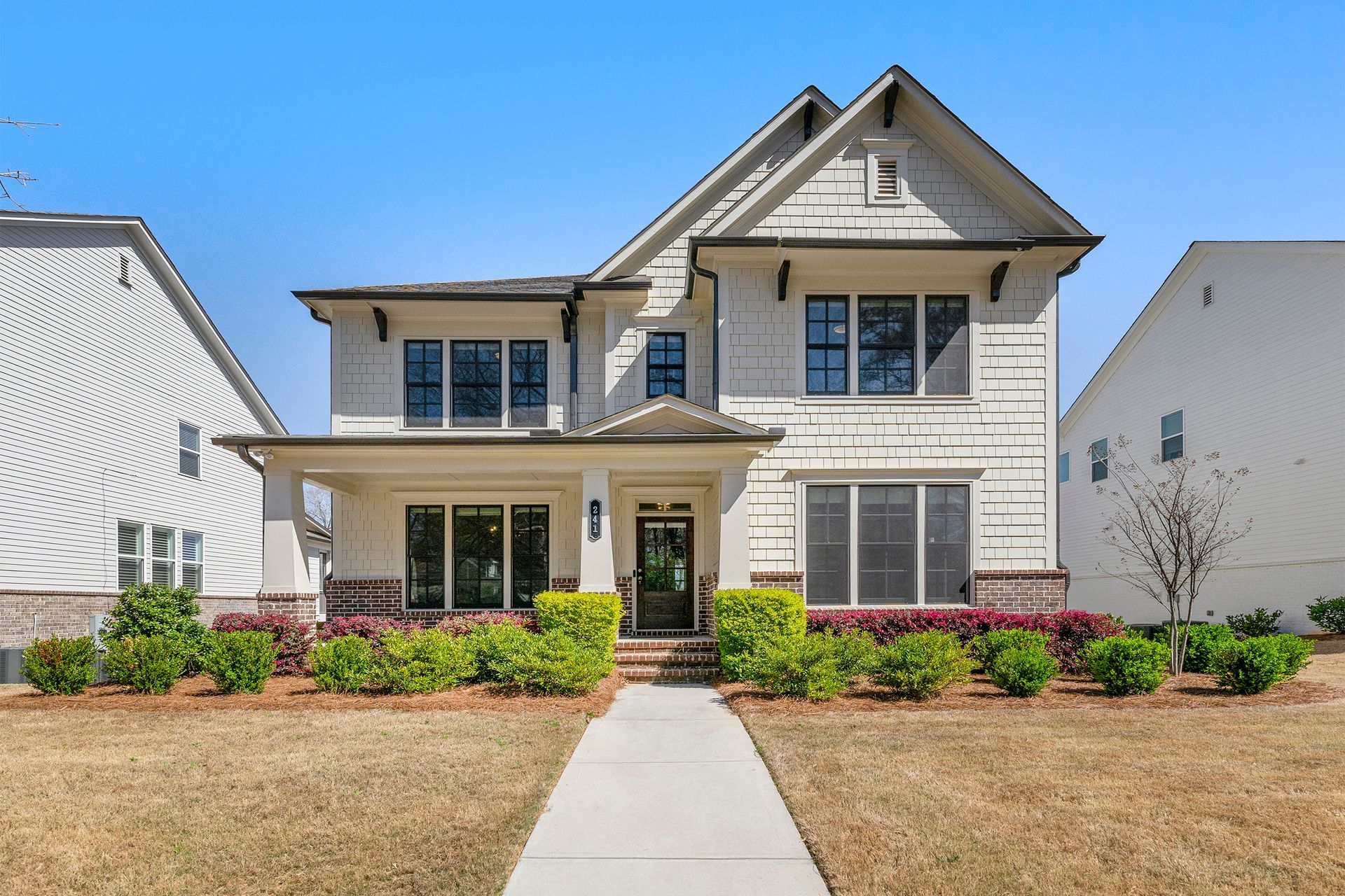 A large white house with a concrete walkway leading to it.