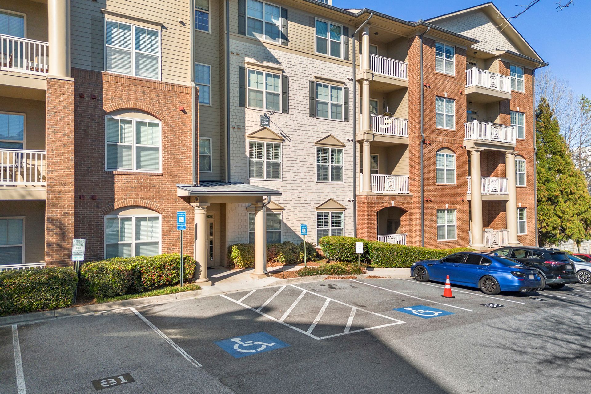 A parking lot in front of a large apartment building with cars parked in front of it.