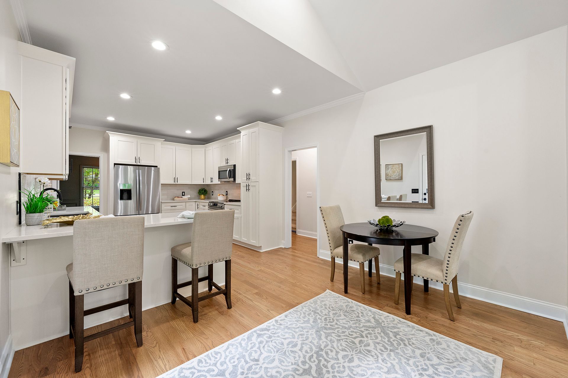 A living room with a table and chairs and a kitchen in the background.