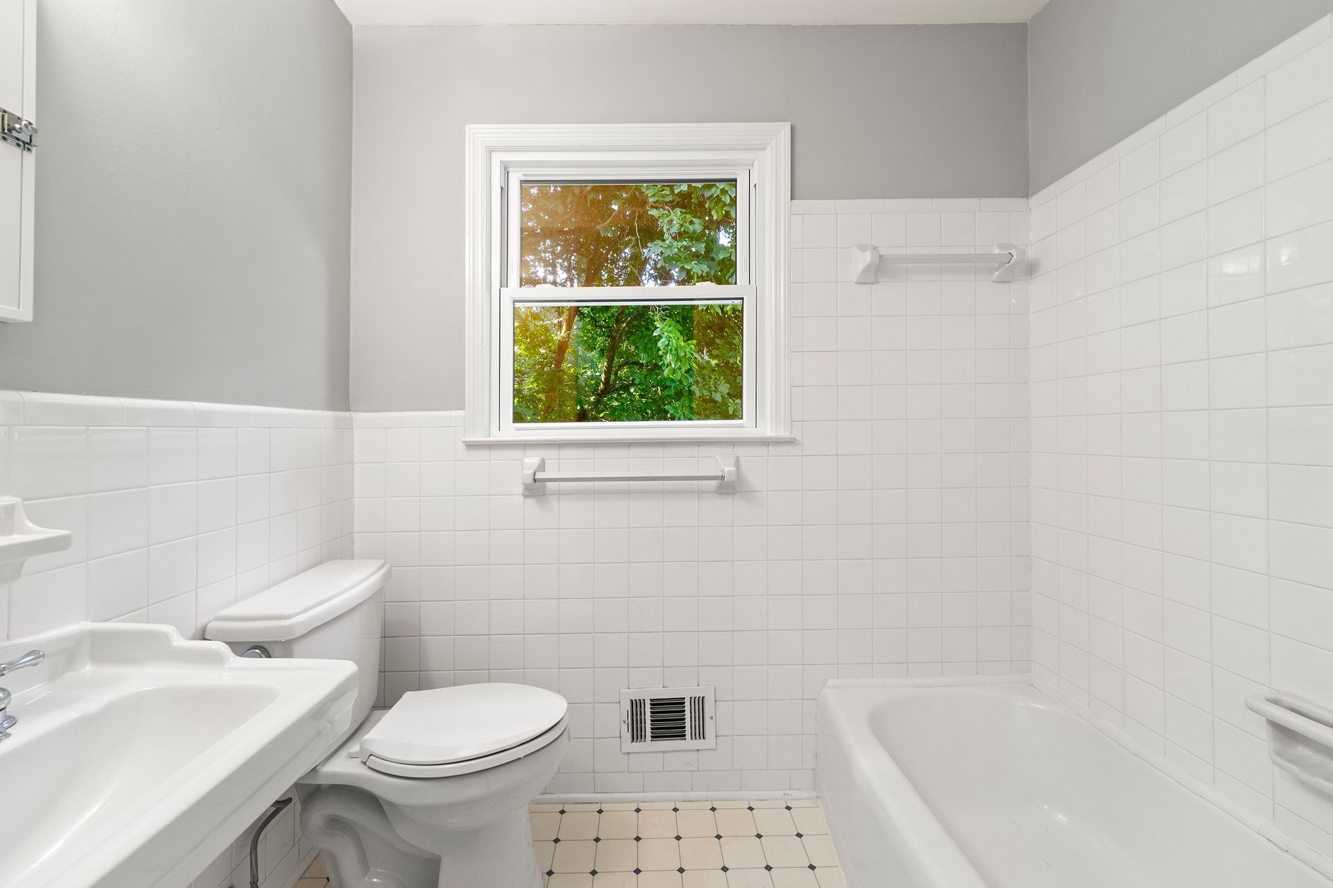 A bathroom with a toilet , sink , bathtub and window.