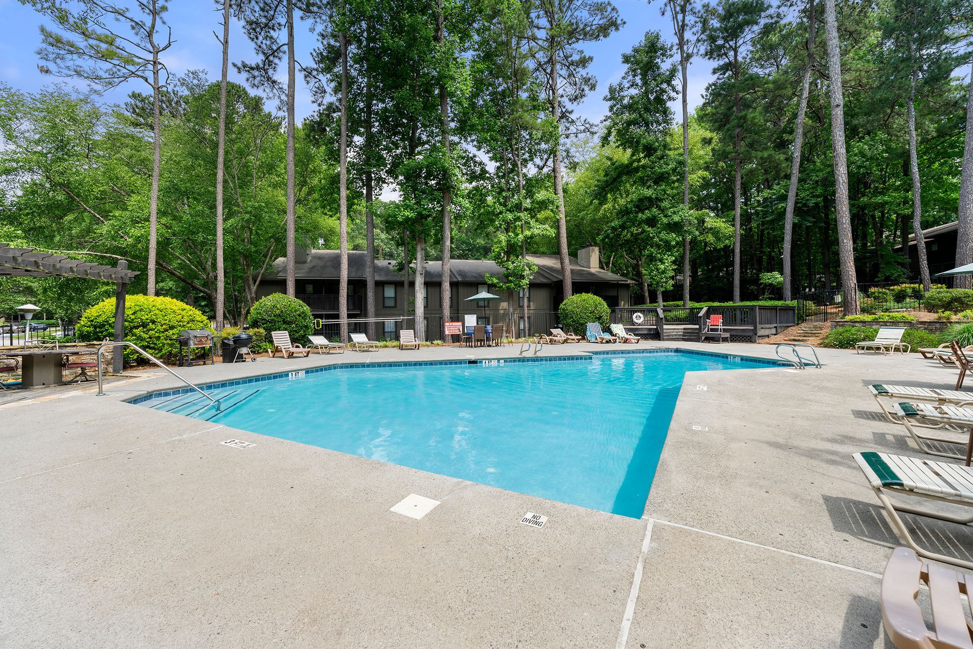 A large swimming pool surrounded by chairs and trees