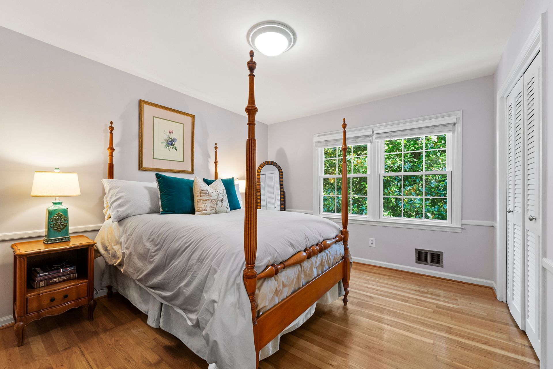 A bedroom with a four poster bed and two windows.