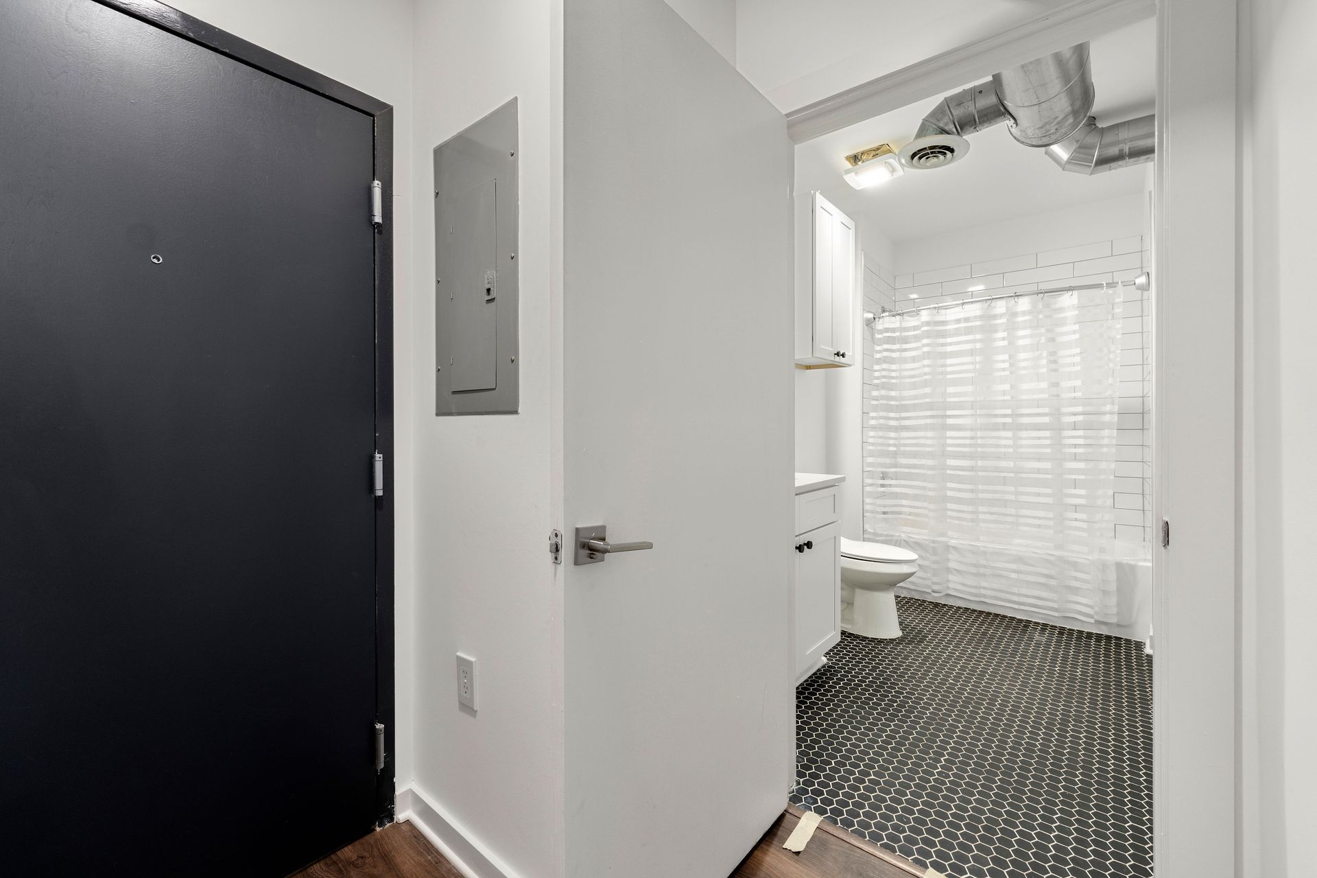A hallway leading to a bathroom with a toilet and shower.