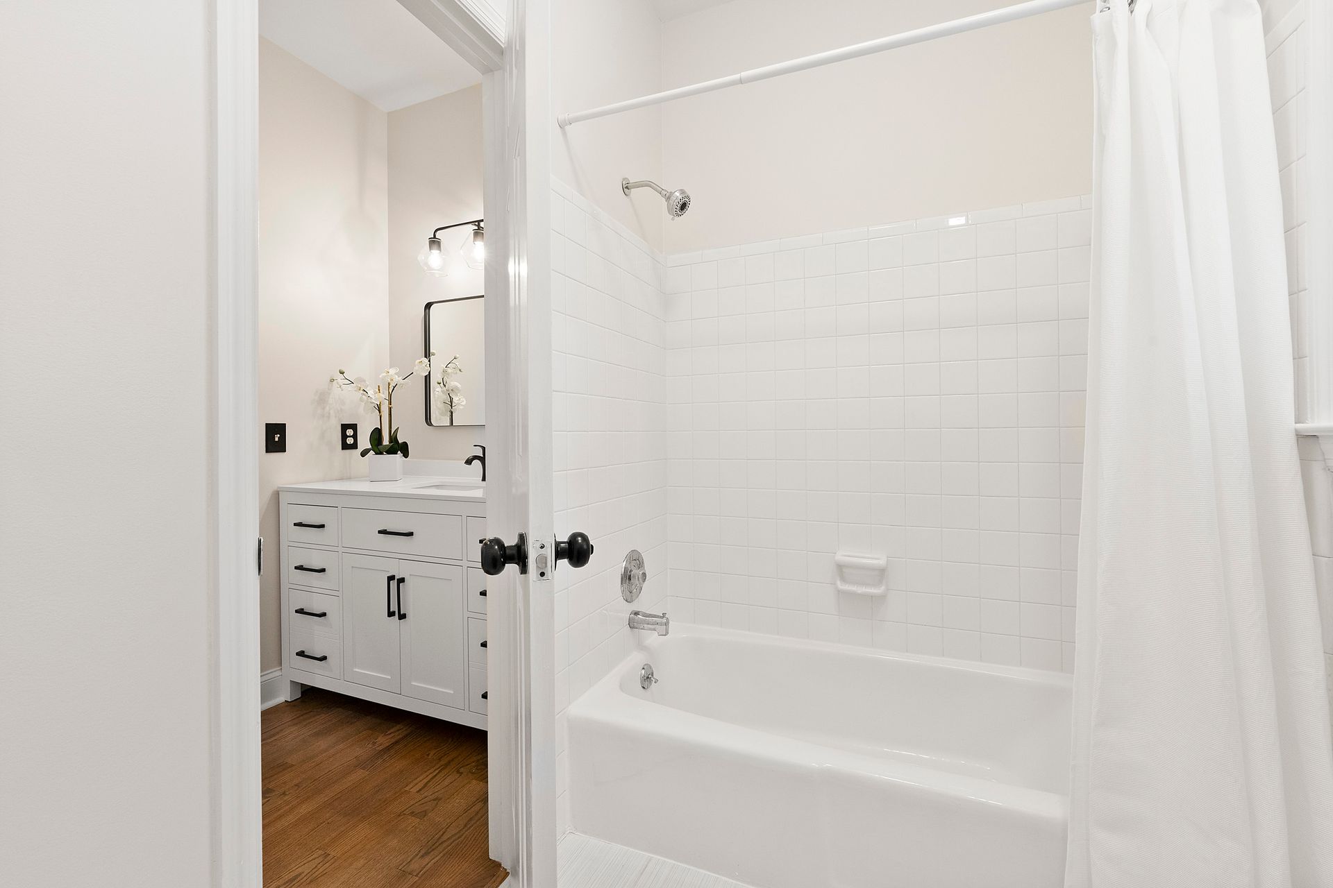 A bathroom with a tub , shower , sink and mirror.