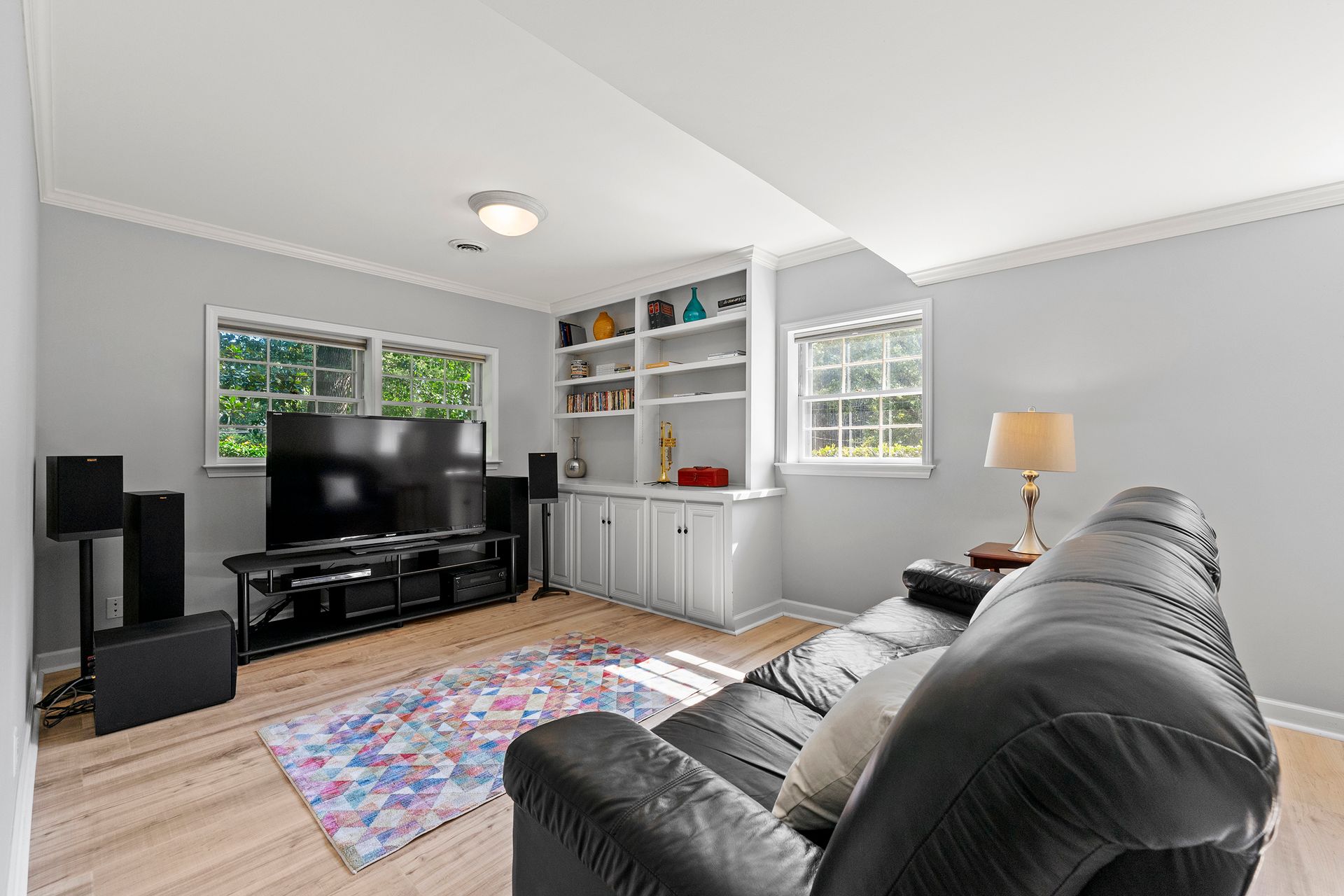 A living room with a black couch and a flat screen tv.