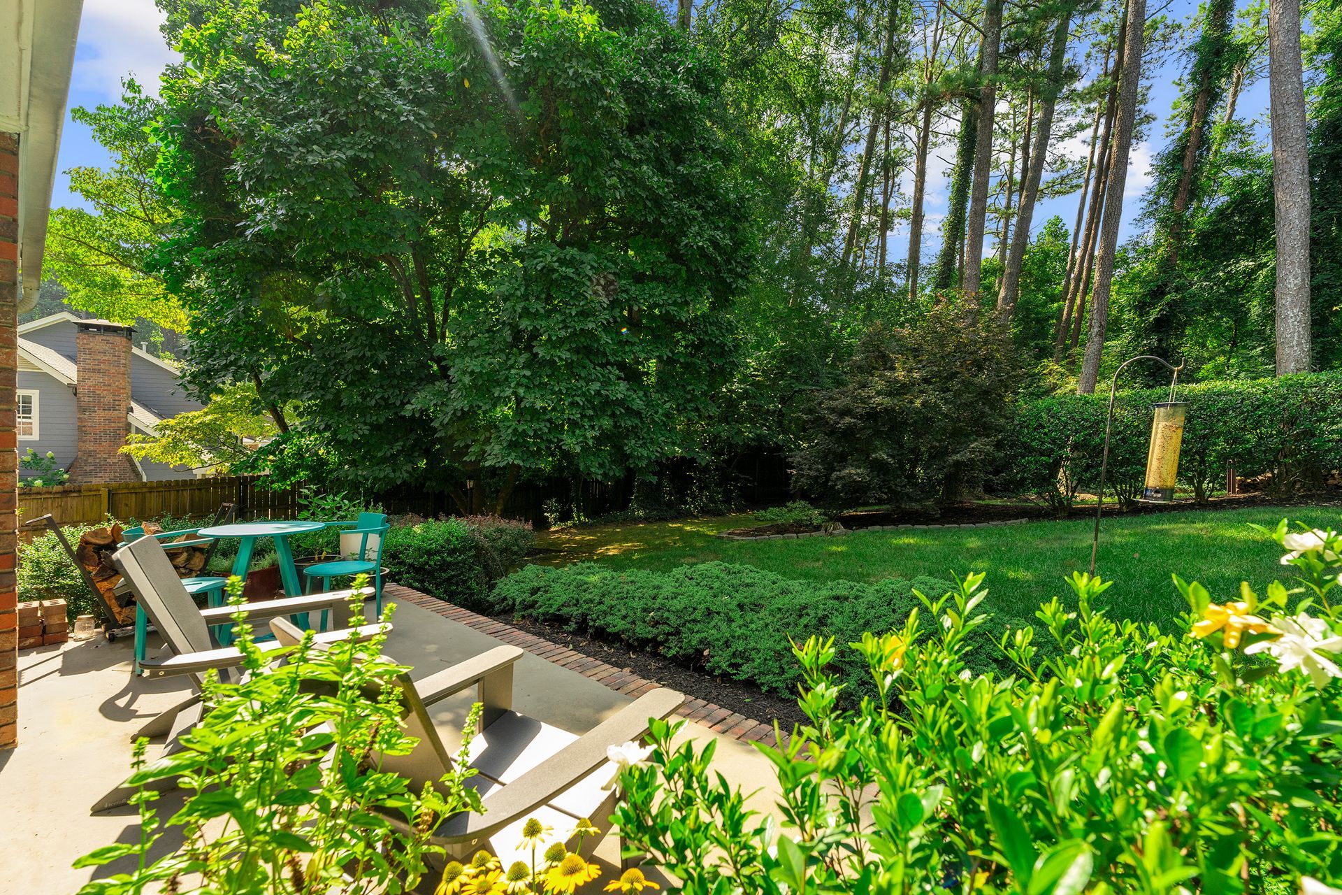 There is a patio with chairs and a table in the backyard.