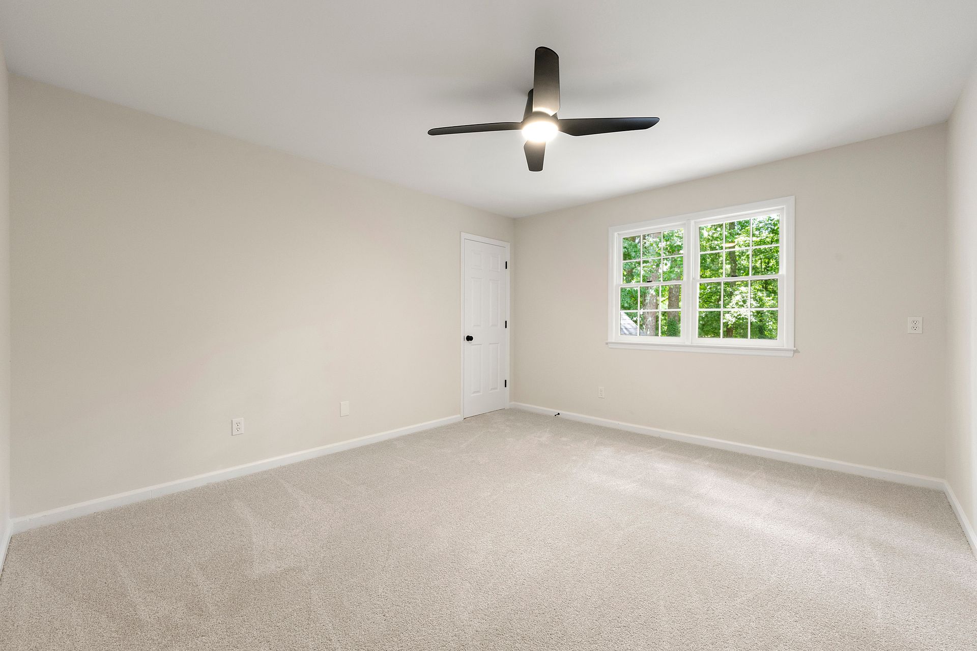 An empty bedroom with a ceiling fan and a window.