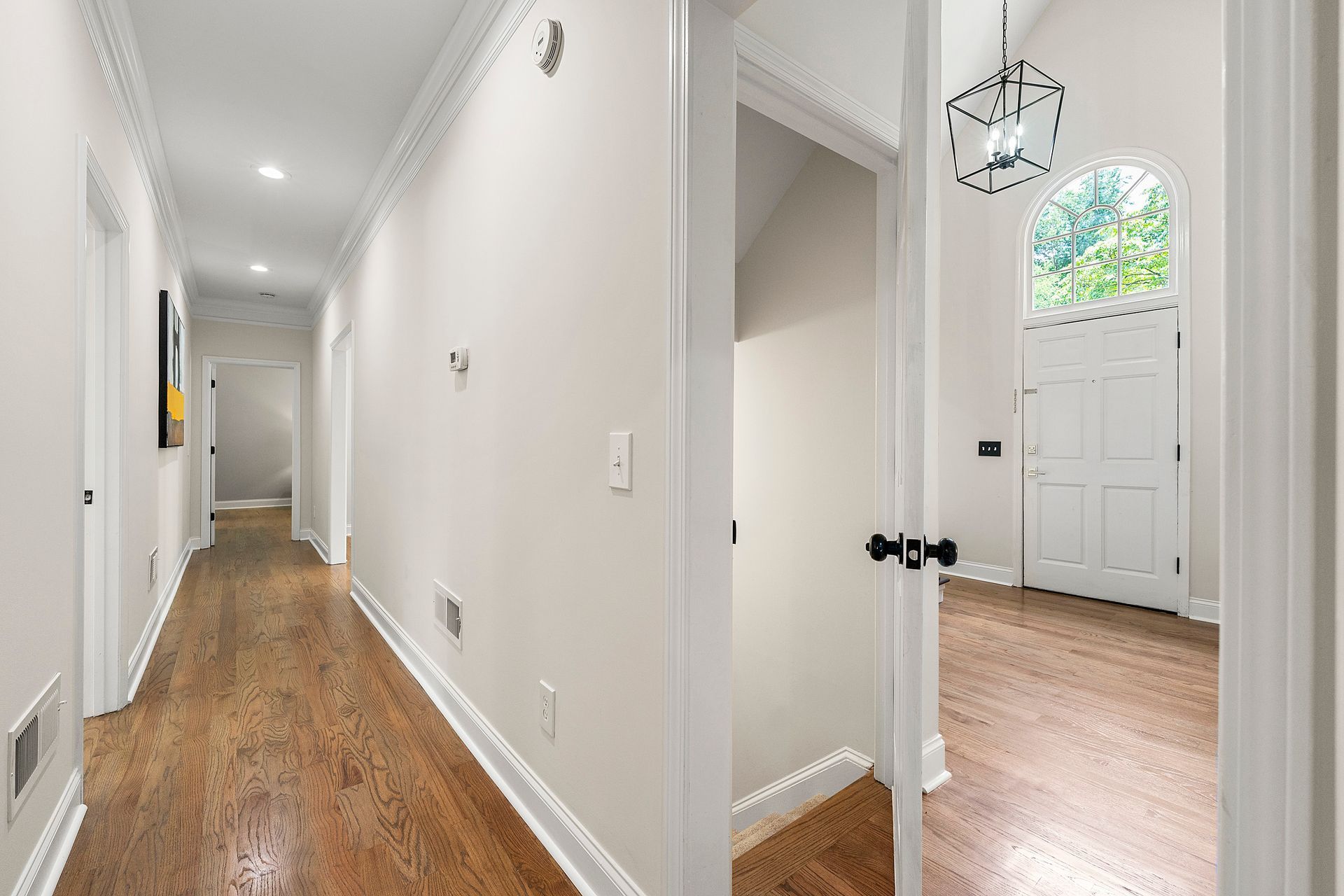 A long hallway with hardwood floors and white walls in a house.