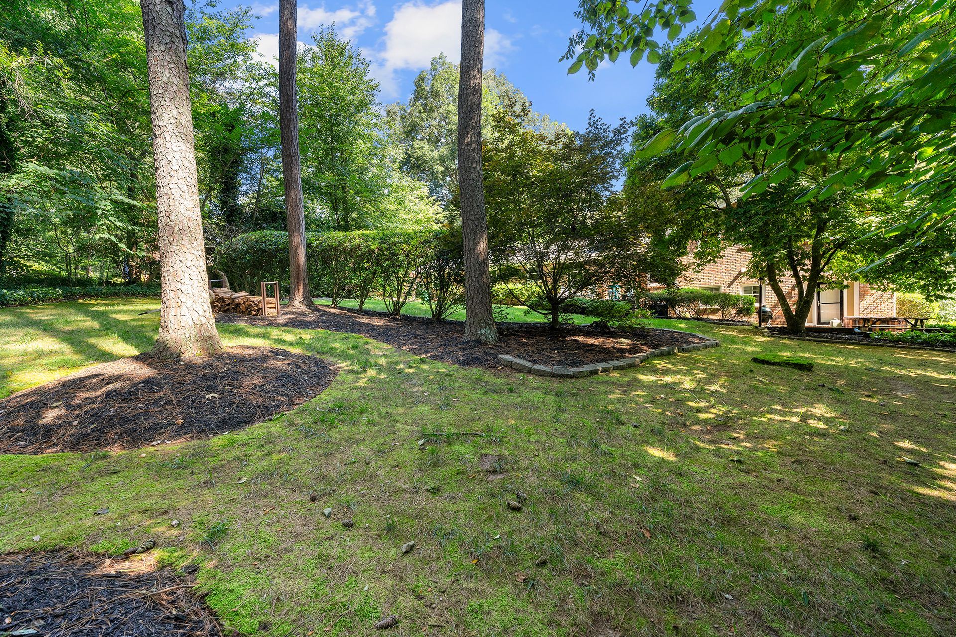 A large lush green yard surrounded by trees and bushes.