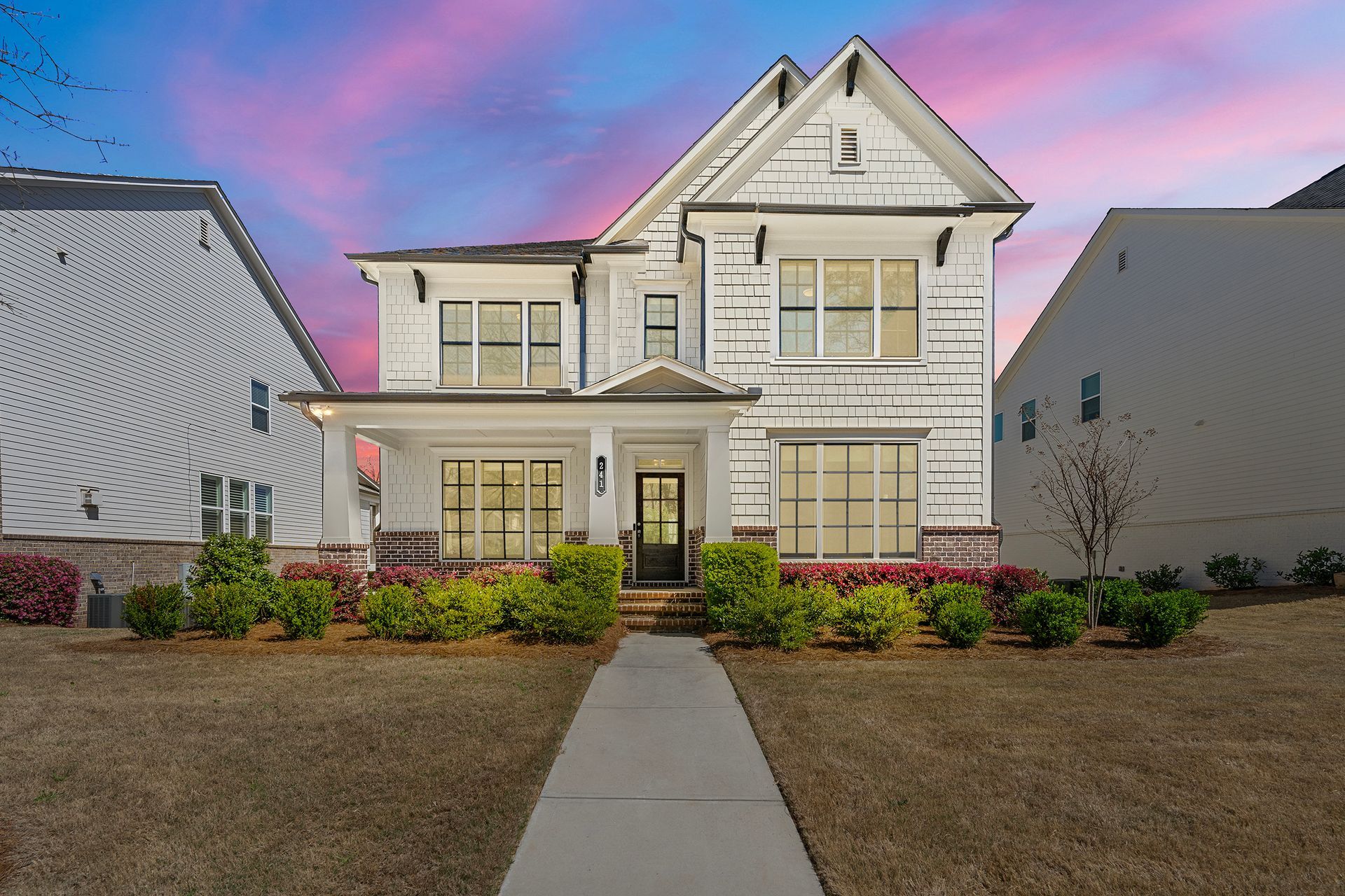 A large white house with a concrete walkway leading to it.