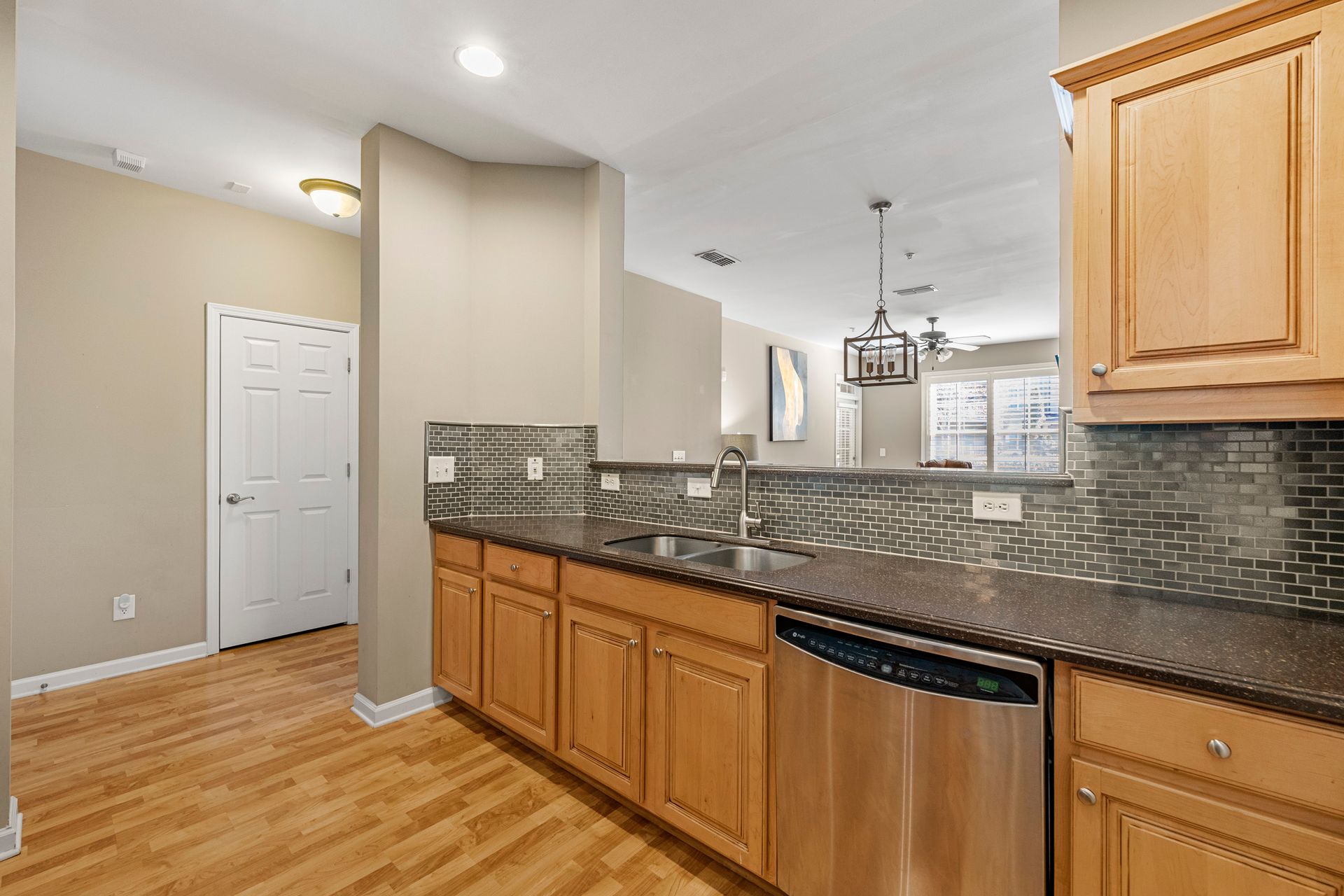 A kitchen with wooden cabinets , granite counter tops , stainless steel appliances and a sink.