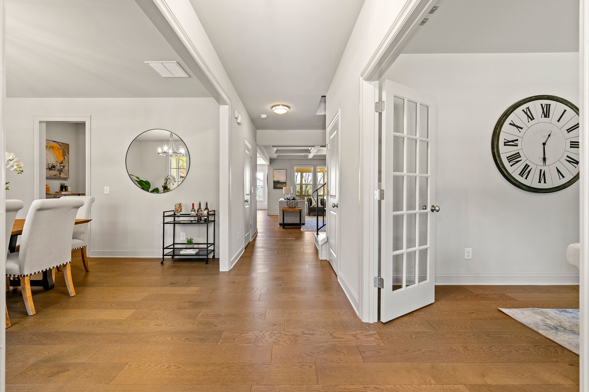 There is a clock on the wall in the middle of the hallway.