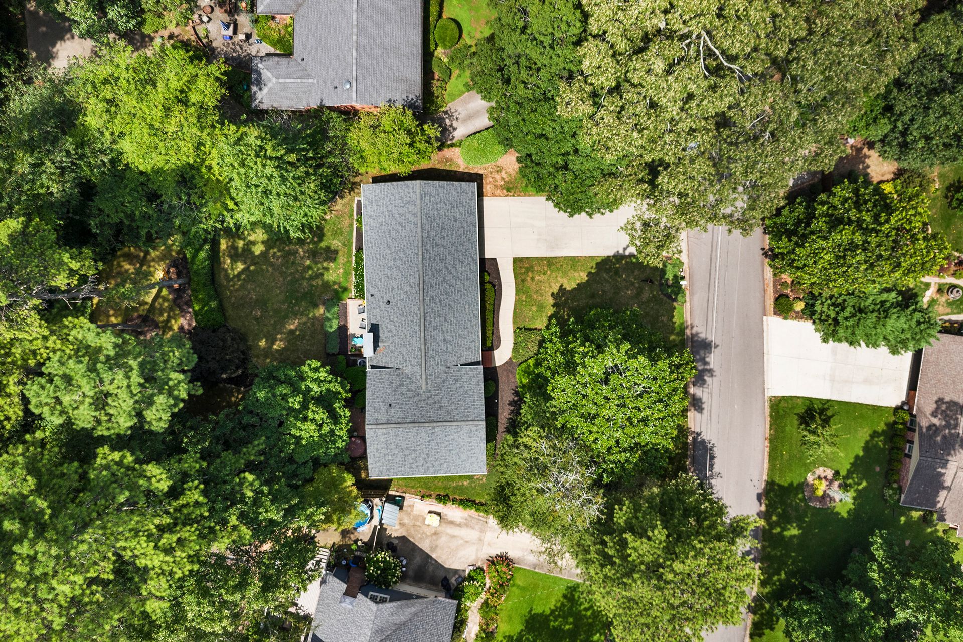 An aerial view of a house in a residential area surrounded by trees.