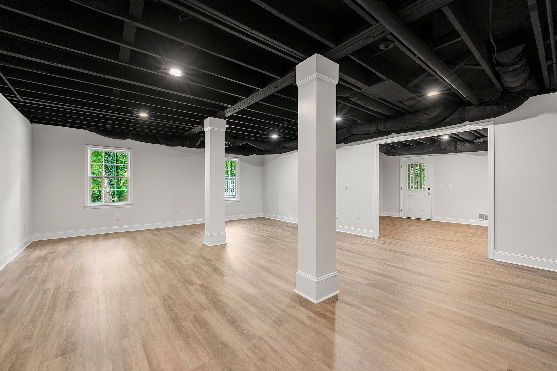 A large empty room with hardwood floors and a black ceiling.