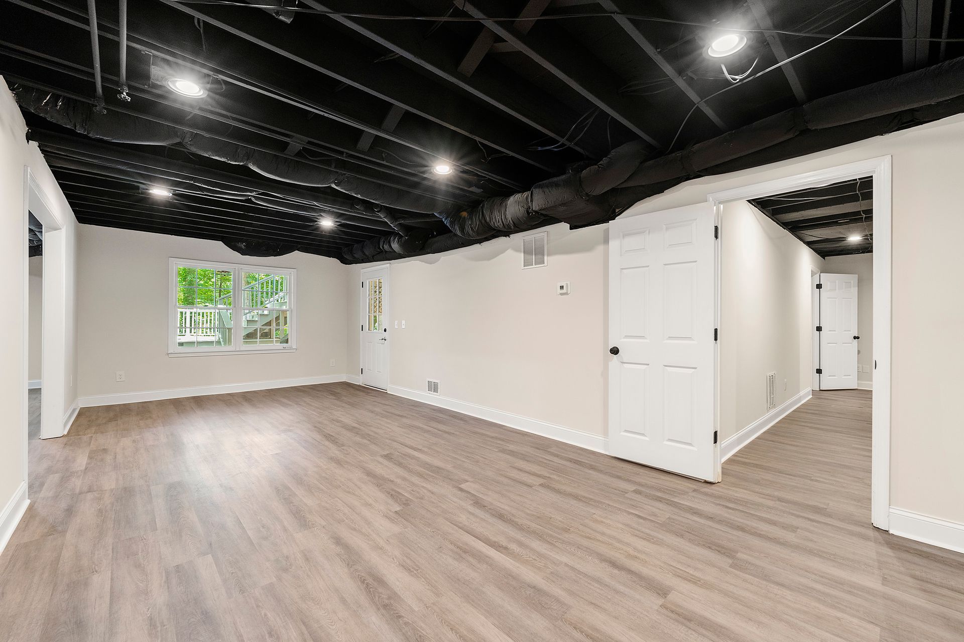 A large empty room with hardwood floors and a black ceiling.