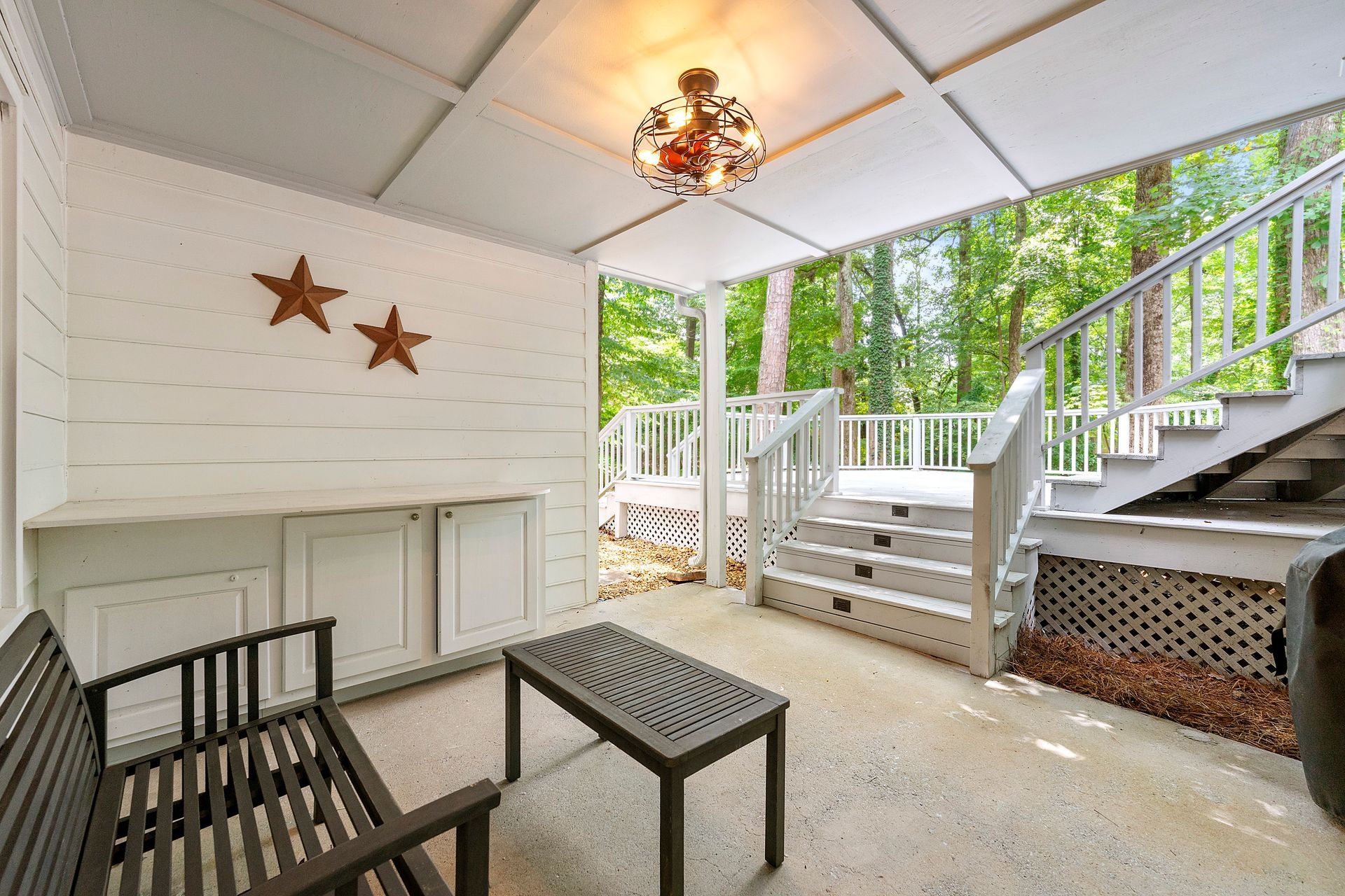A porch with a bench , table , and stairs.