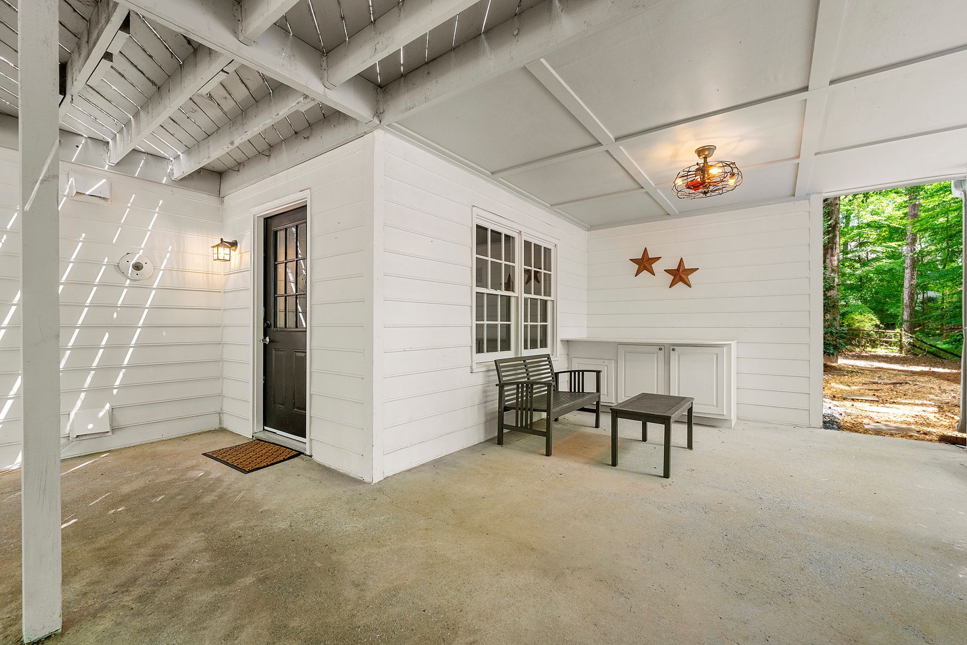 A white house with a porch with chairs and a table.