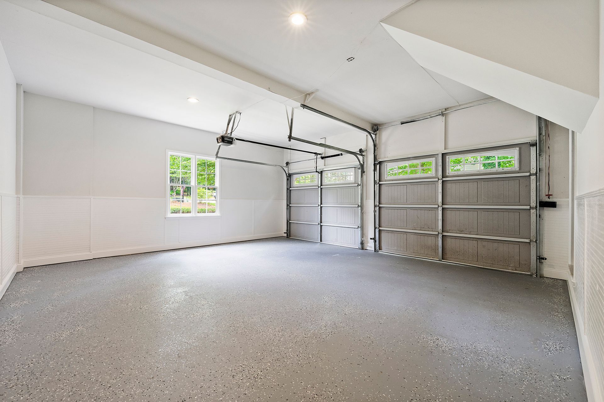 An empty garage with a garage door open and a window.