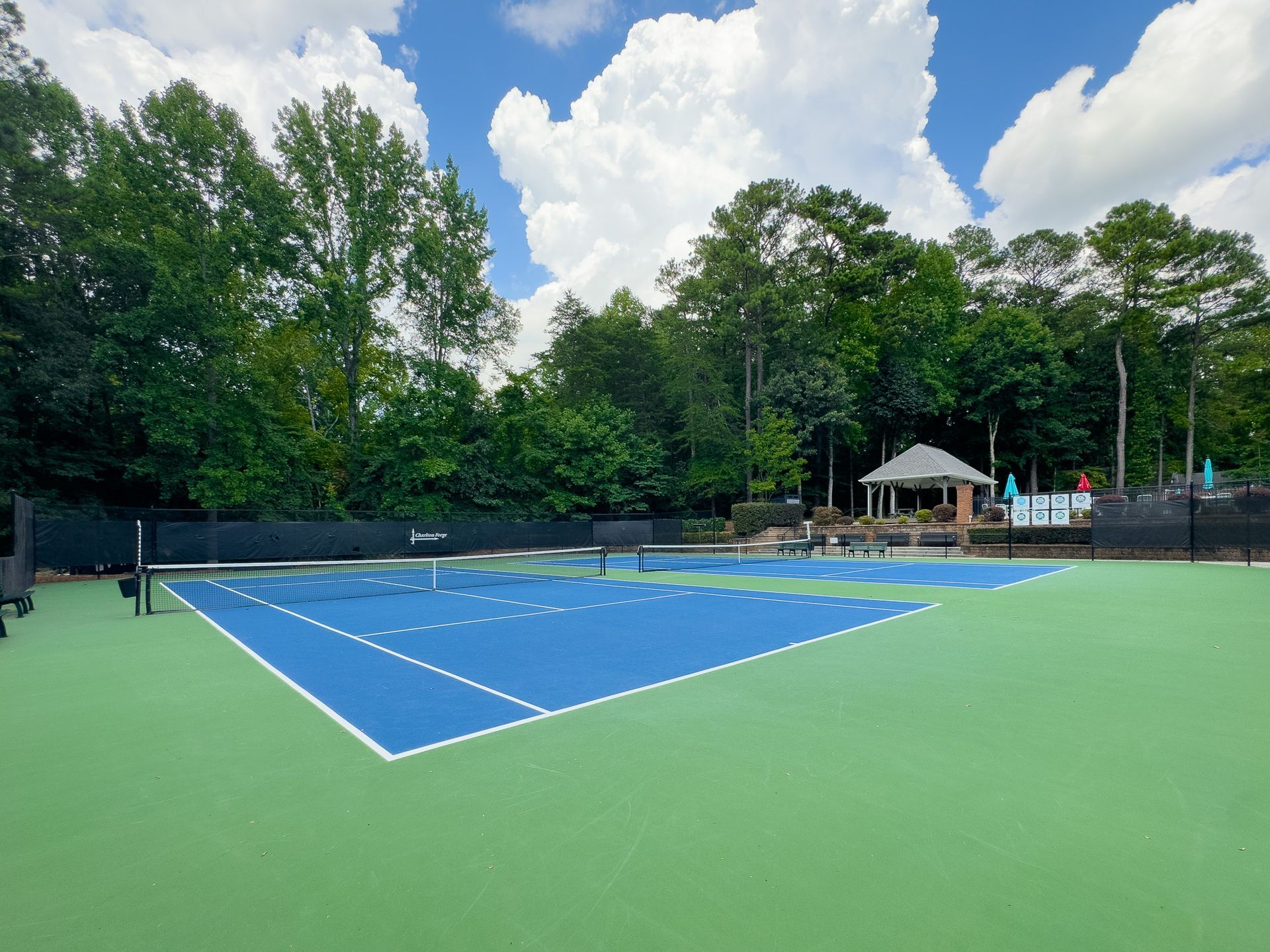 A tennis court with a gazebo in the background