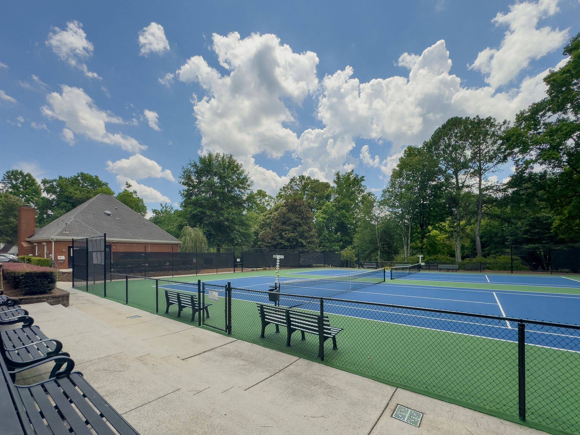 A tennis court with a fence and benches in front of it
