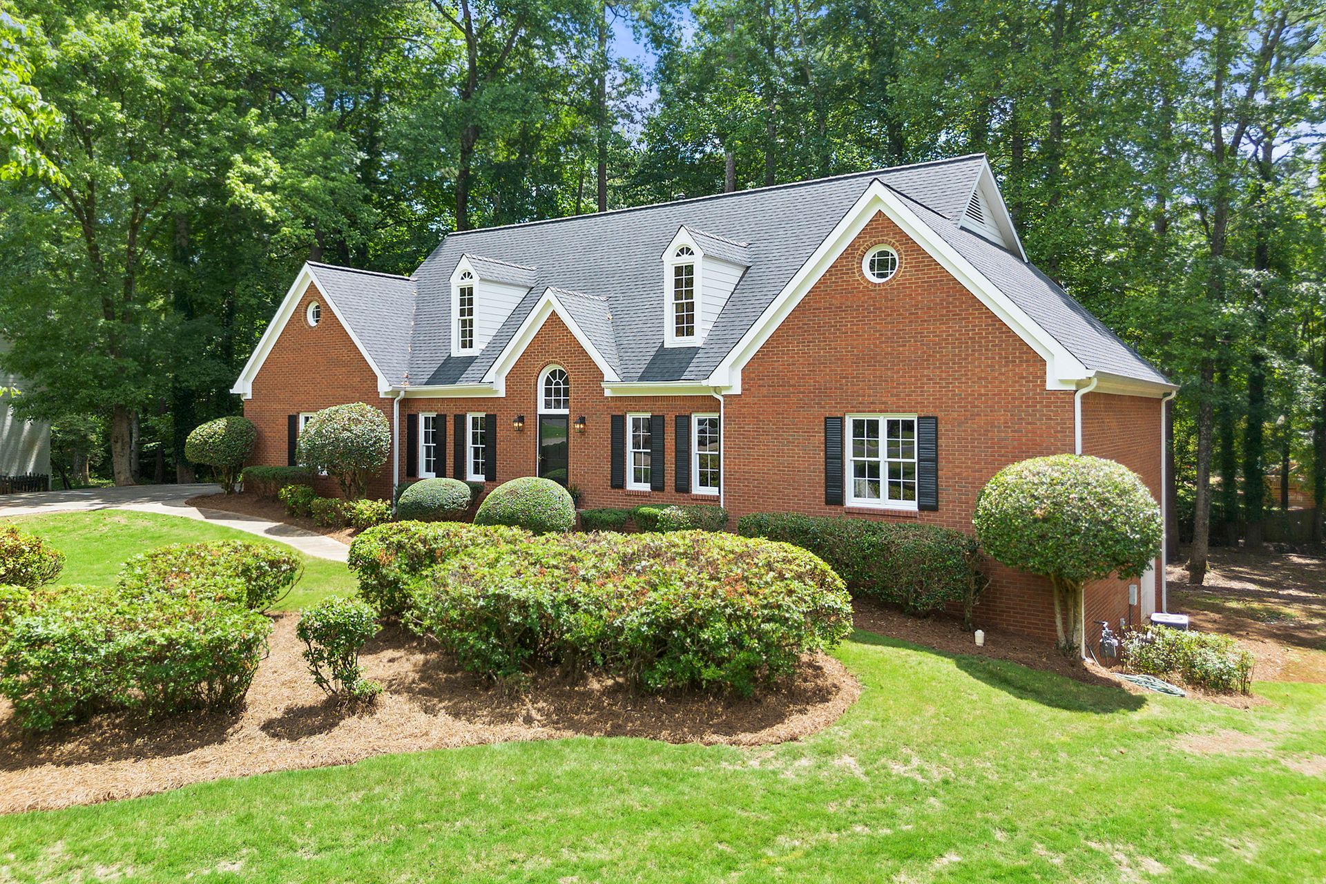 A large brick house with a lush green lawn in front of it.