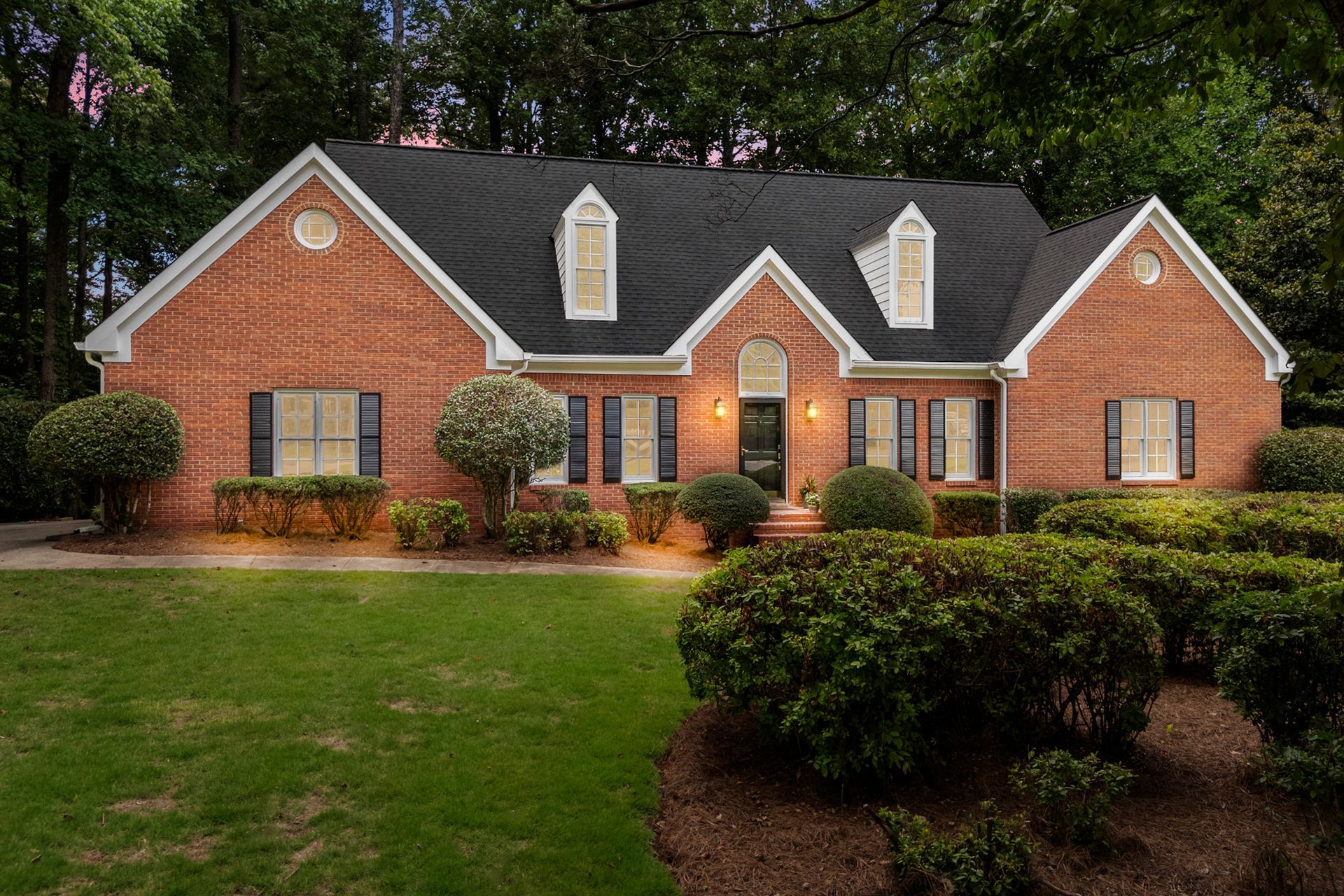 A large brick house with a black roof and white shutters