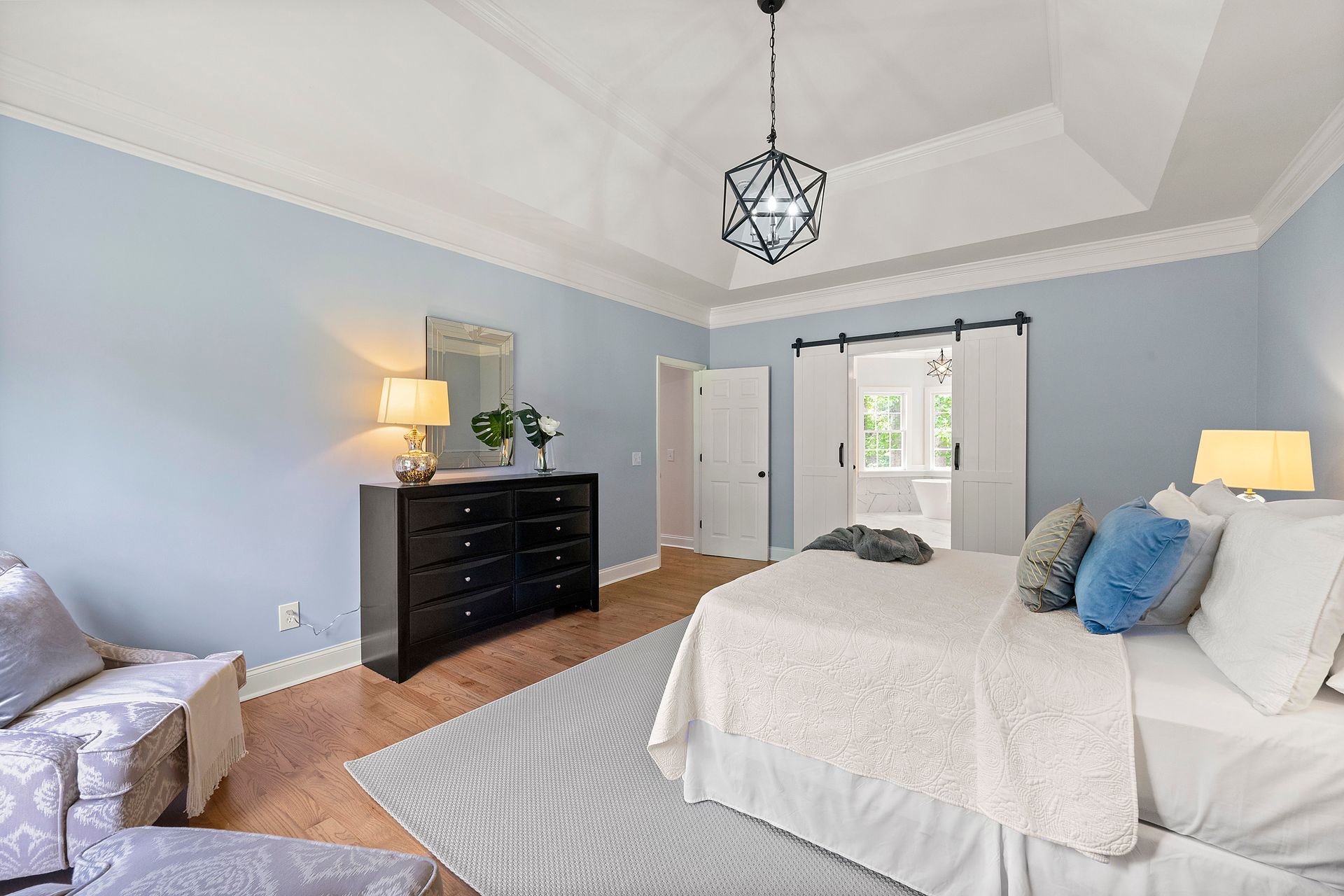 A bedroom with a large bed , dresser , chair and rug.