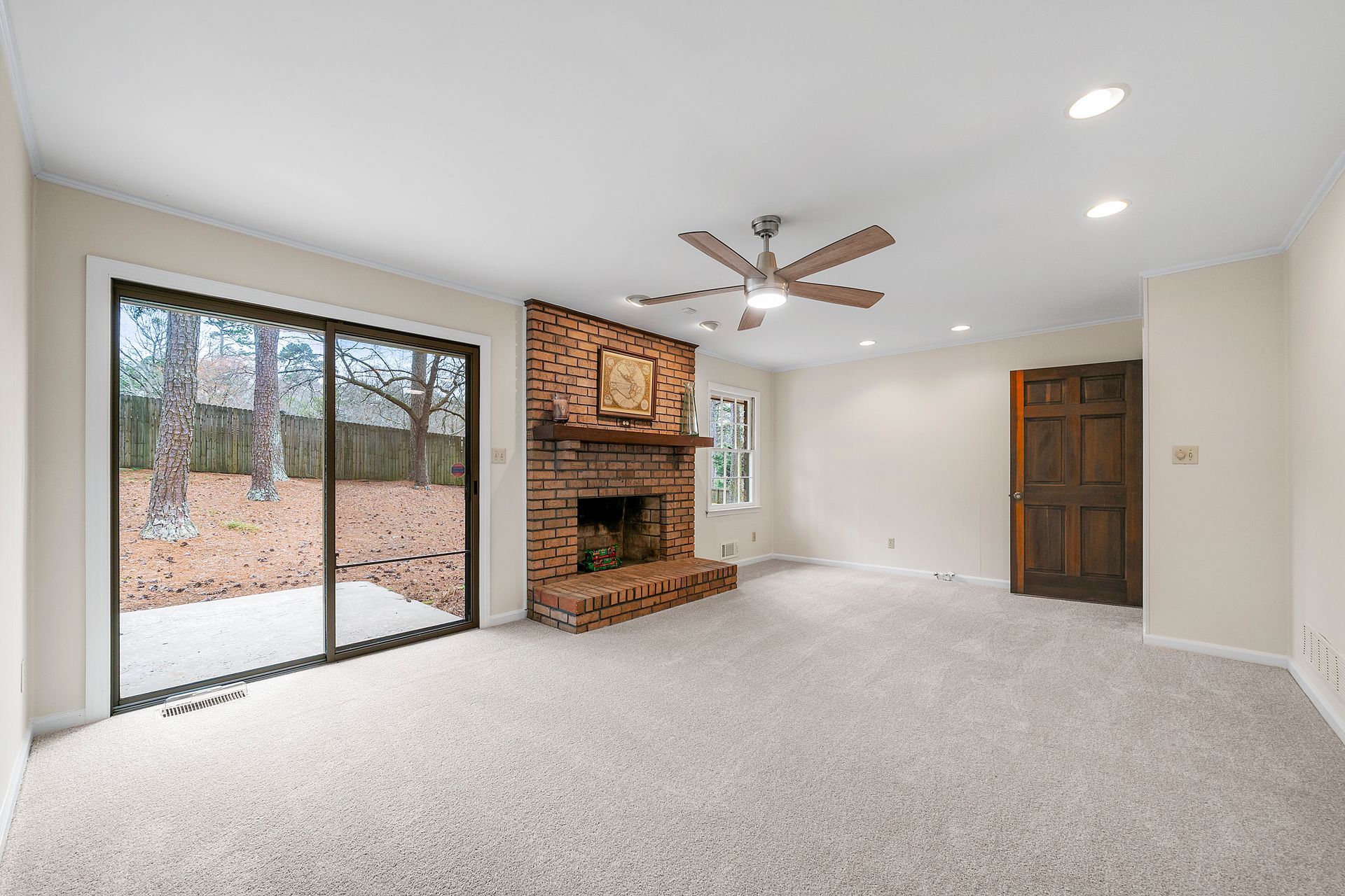 An empty living room with a fireplace and a ceiling fan.