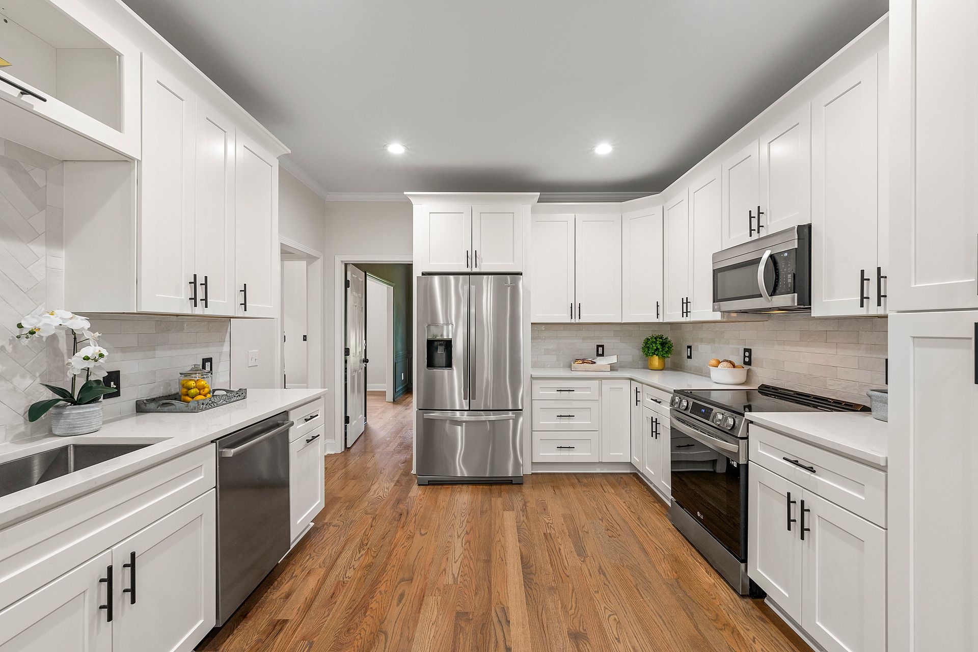 A kitchen with white cabinets , stainless steel appliances , and hardwood floors.