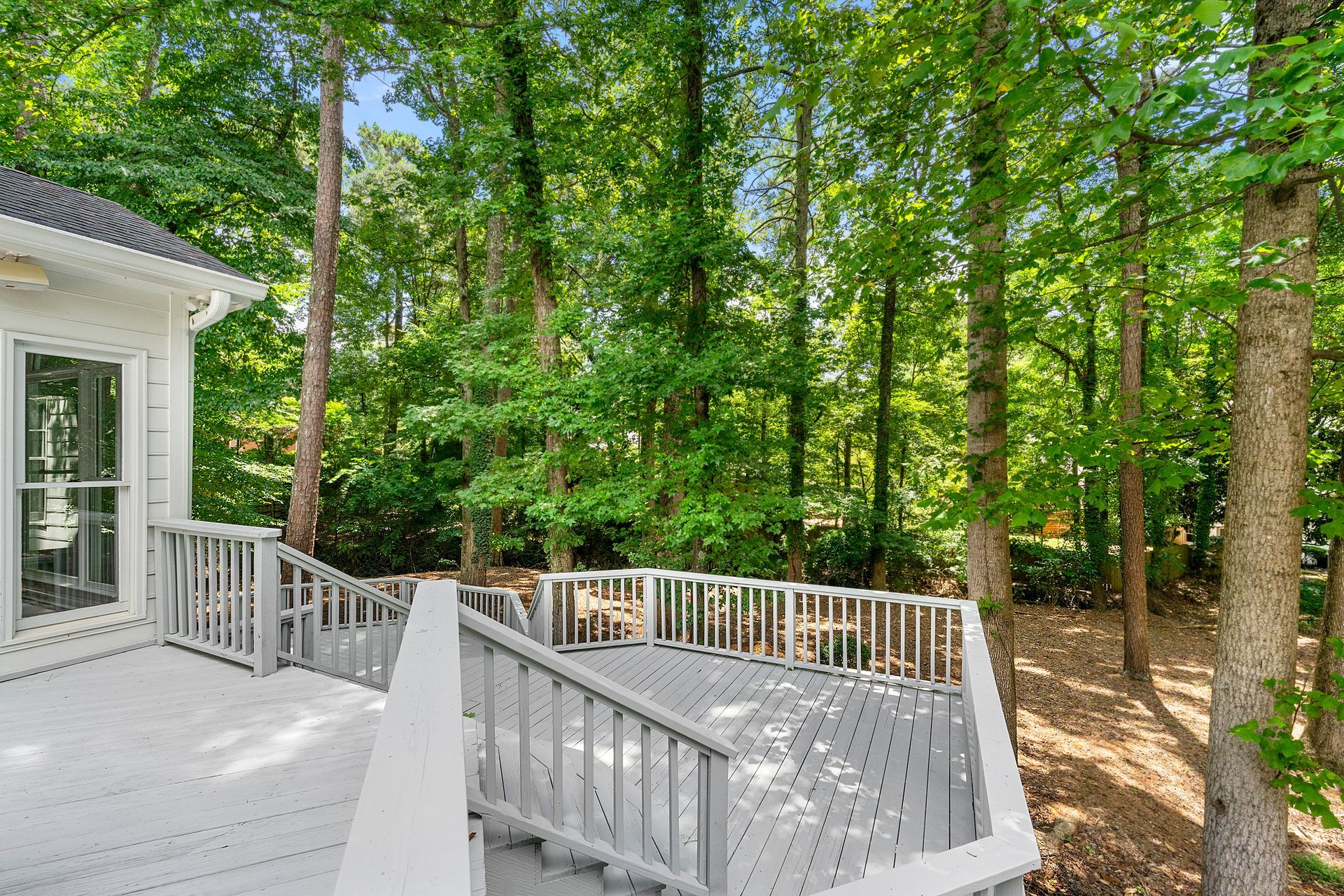 A deck with stairs leading up to it is surrounded by trees.