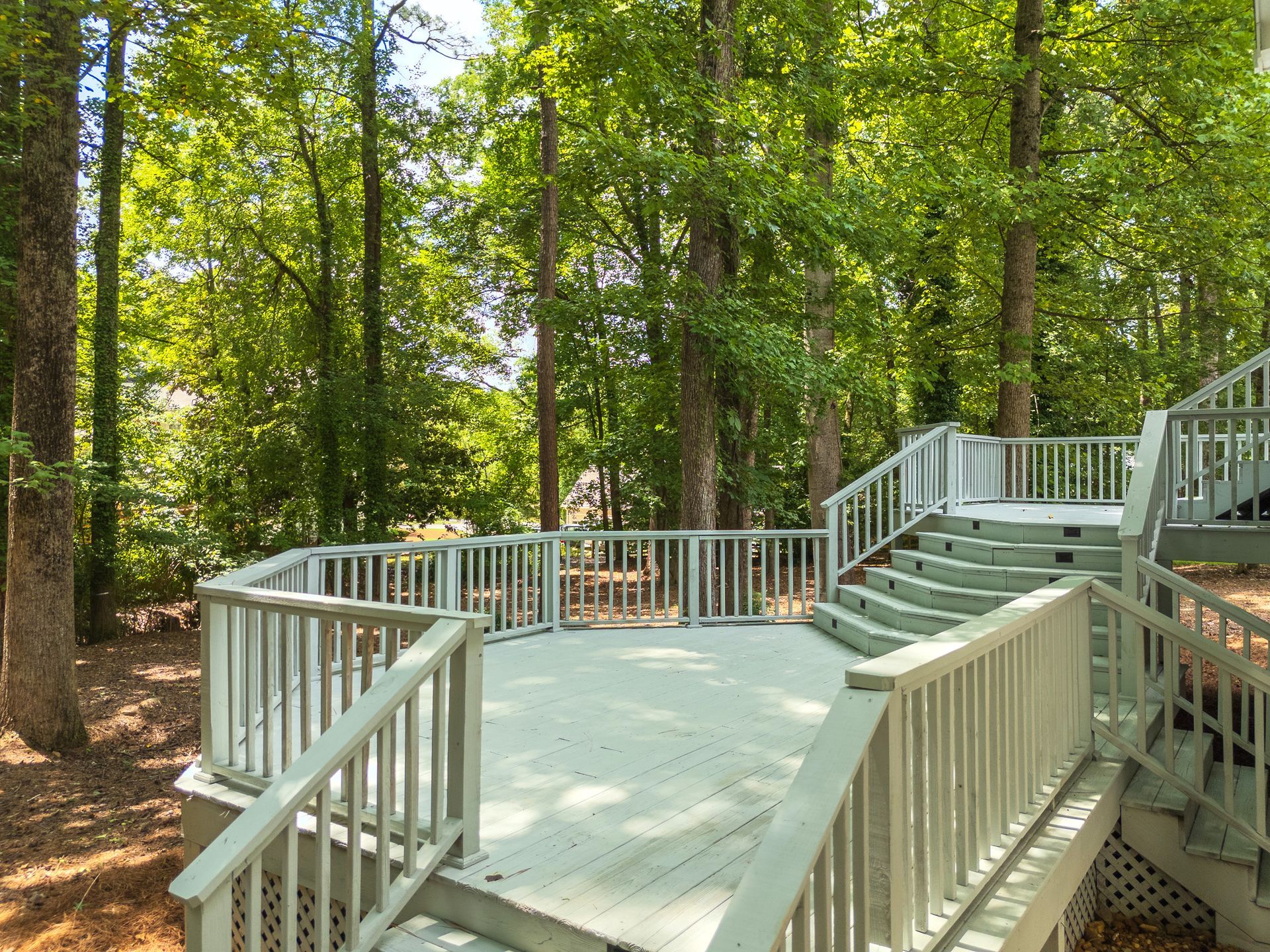 A wooden deck with stairs leading up to it in the middle of a forest.