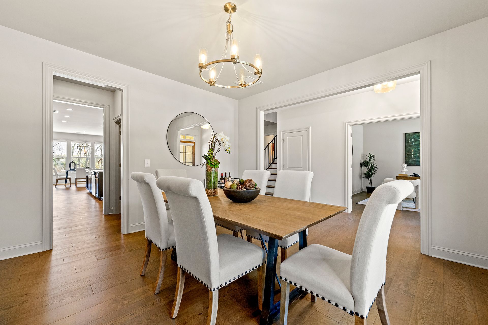 A dining room with a wooden table and white chairs and a chandelier.